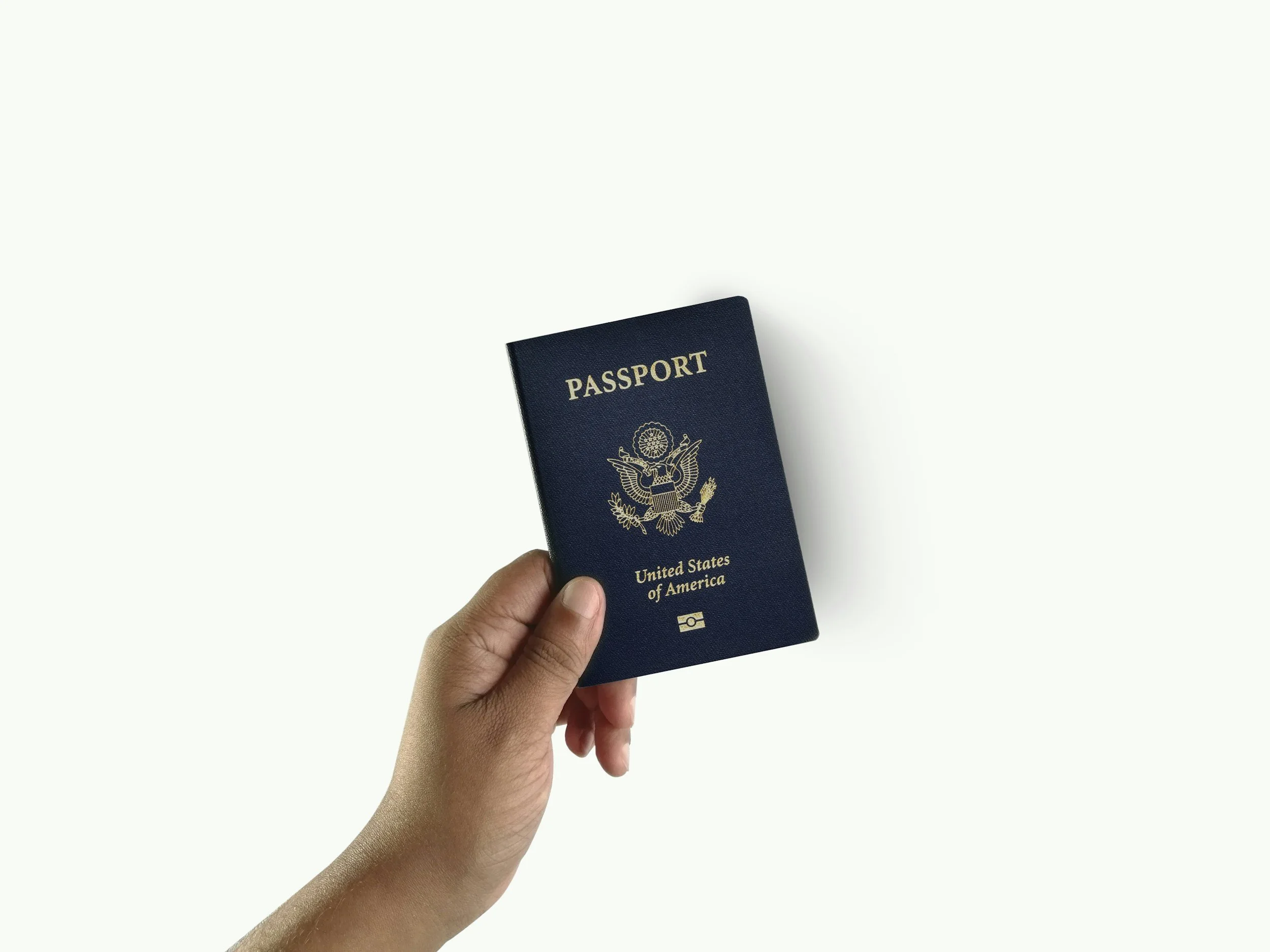 Hand holding a United States passport against a plain white background.