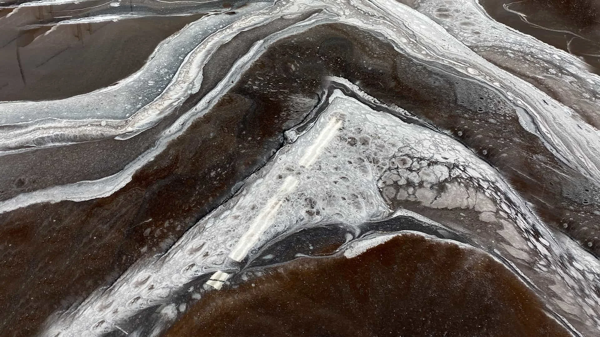 Close-up view of a polished slab of natural stone with swirling patterns in black, white, and gray colors.