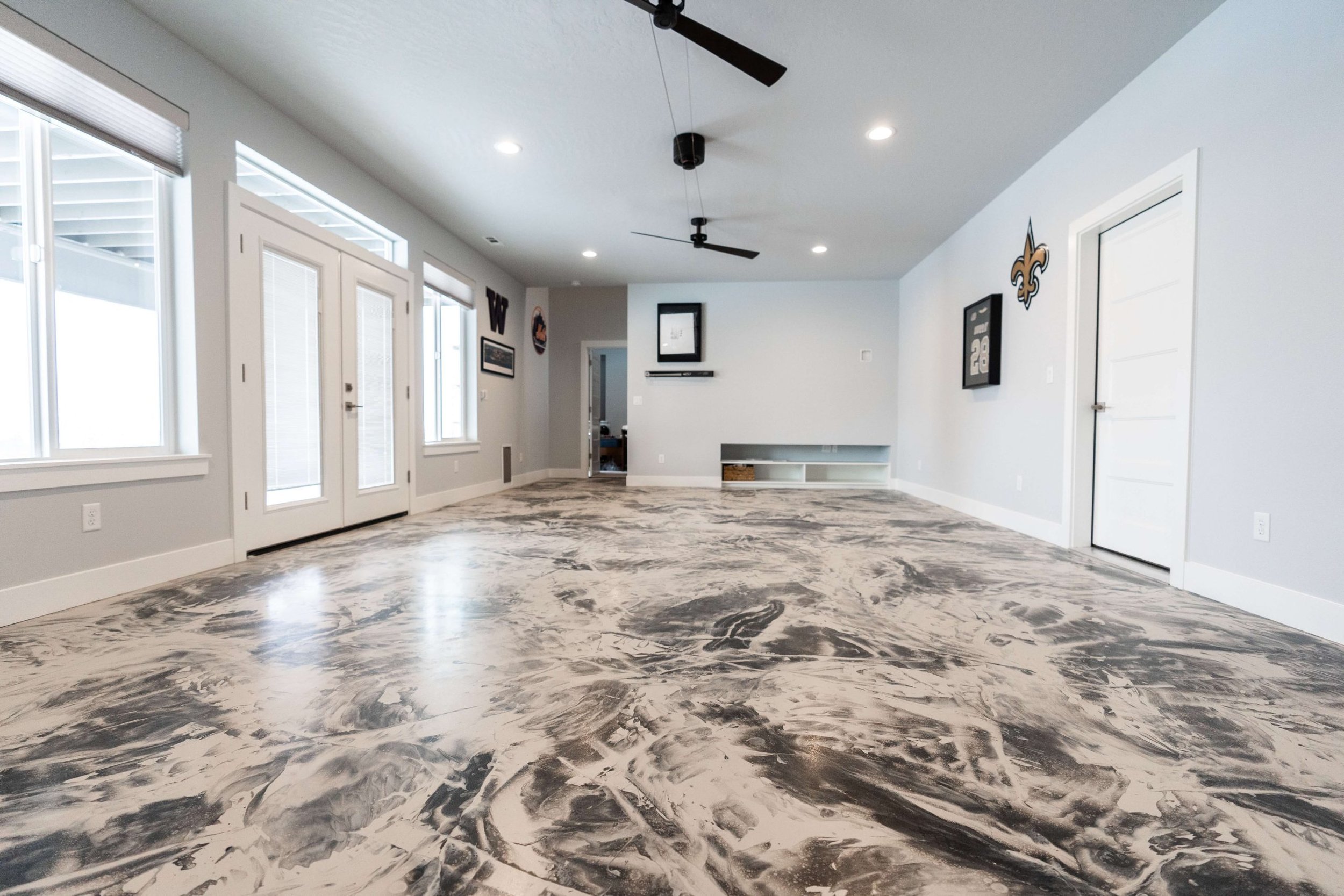 Spacious empty living room with marble floor, white walls, large windows, and ceiling fans.