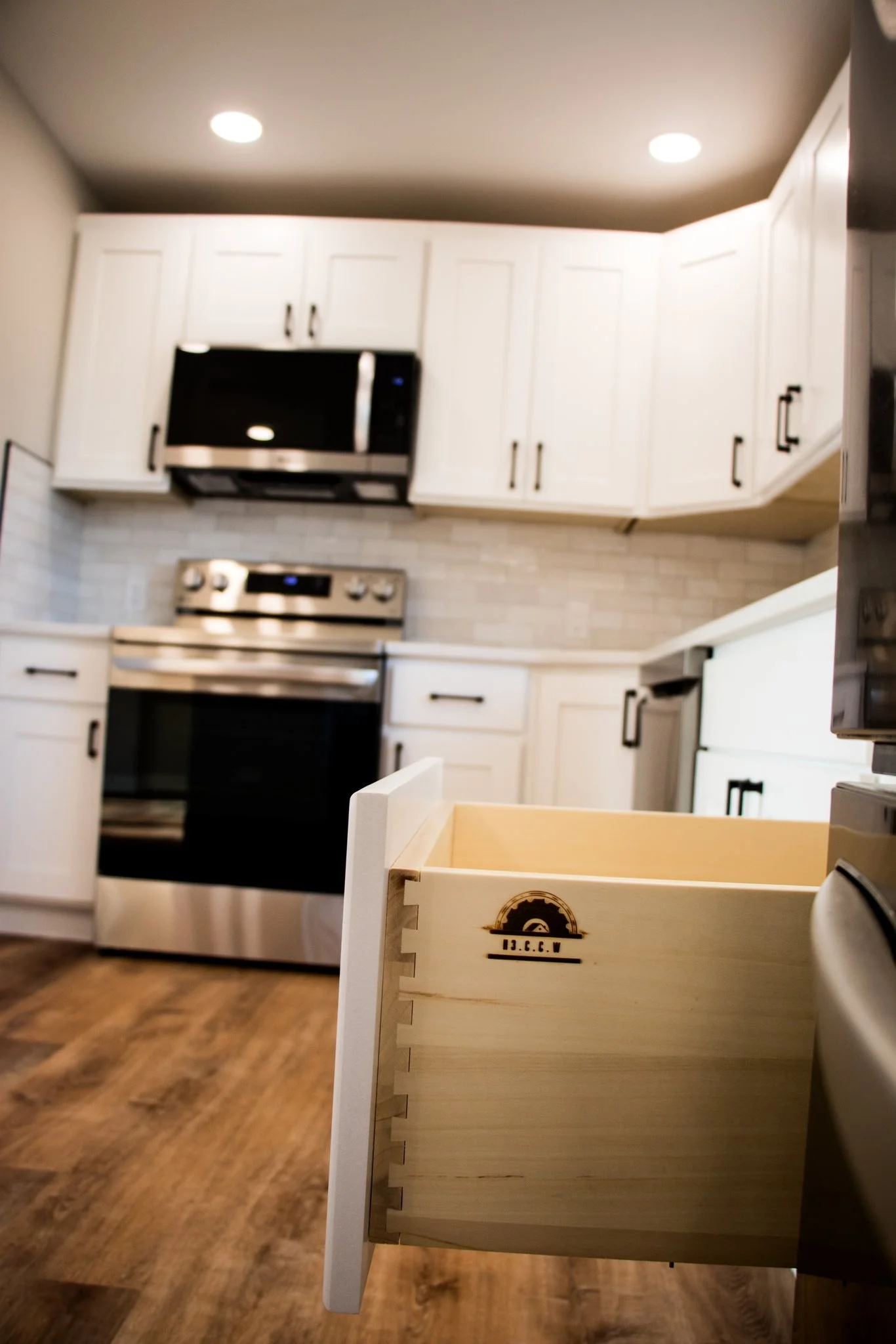 Kitchen with white cabinets, stainless steel appliances, and an open wooden drawer.