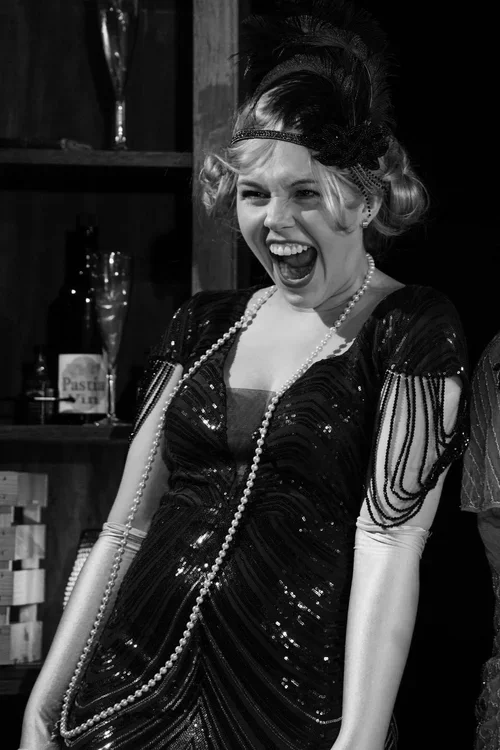 Woman wearing 1920s flapper dress and headpiece, laughing/Getty