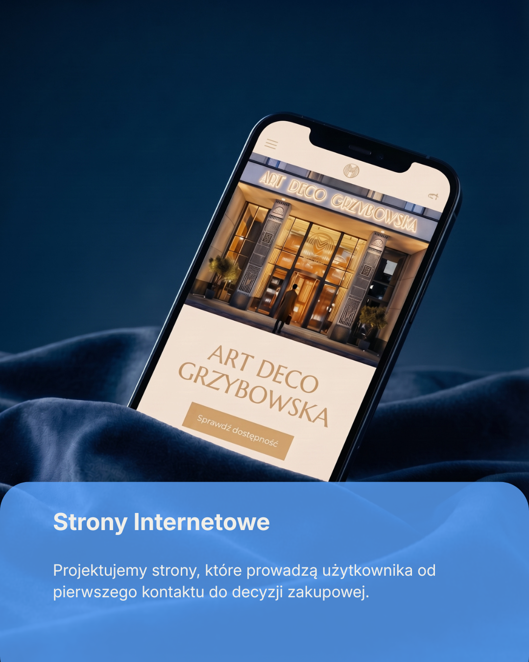 Smartphone displaying a website for Art Deco Grzybowska, showing a stylish building entrance and a button to check availability. The background includes a dark, silky fabric surface.