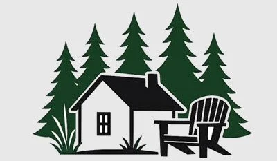 A black and white house with a porch surrounded by tall pine trees and a wooden outdoor chair in the foreground.