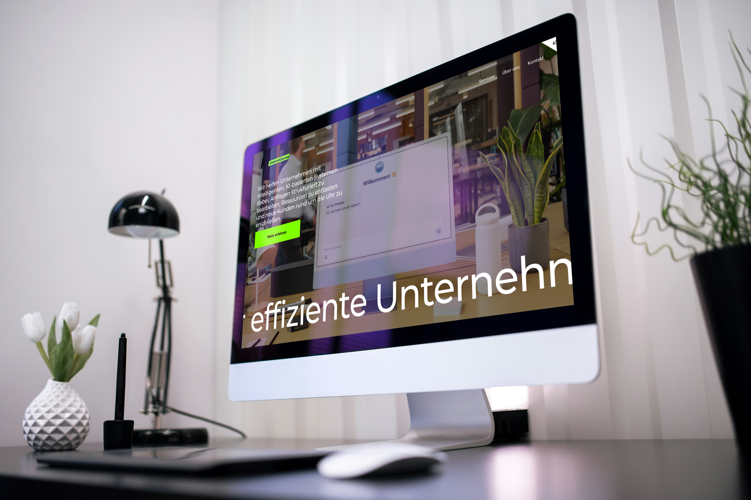 Ein Computerbildschirm zeigt eine Webseite mit dem Text 'effiziente Unternehmen'. Der Schreibtisch hat eine Vase mit weißen Tulpen, eine schwarze Lampe, einen Stift und ein Tablet. Im Hintergrund sind Pflanzen und ein schlichter Raum.