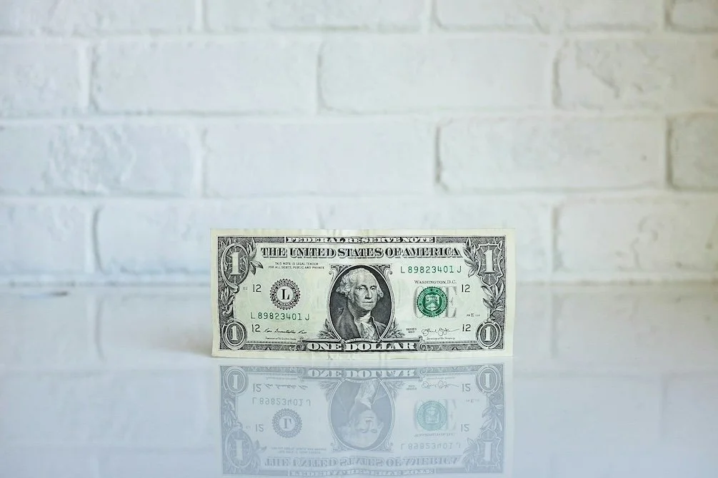 dollar bill against a white brick background