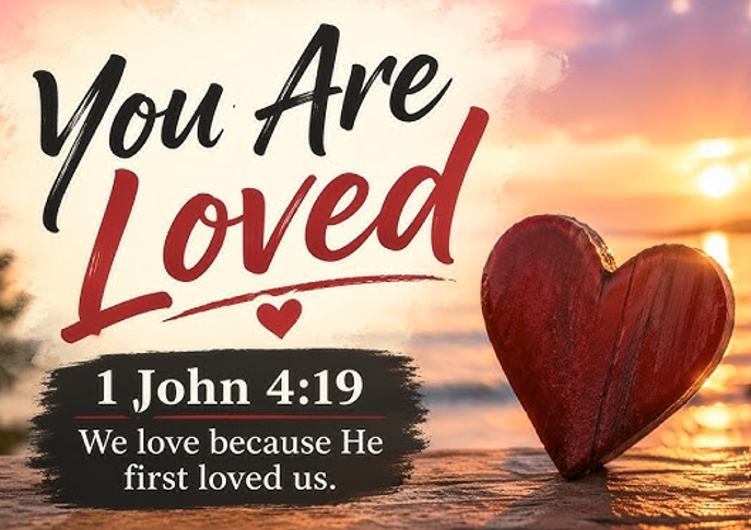 A sunset over water with a wooden heart on the shore and the text 'You Are Loved', including a Bible verse from 1 John 4:19 stating 'We love because He first loved us.'