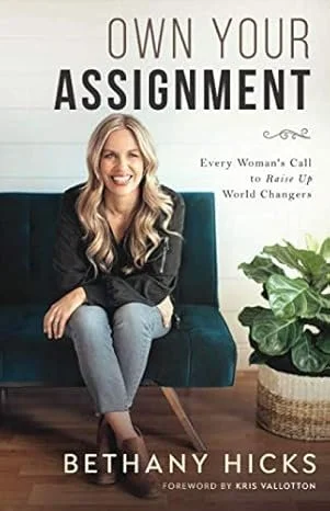Book cover for "Own Your Assignment" by Bethany Hicks, featuring a smiling woman sitting on a teal chair with a houseplant nearby.