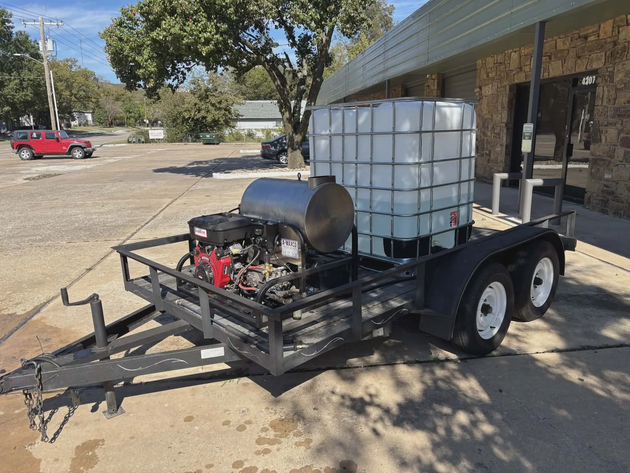 A trailer with a large water tank and a generator unit parked outside a building.