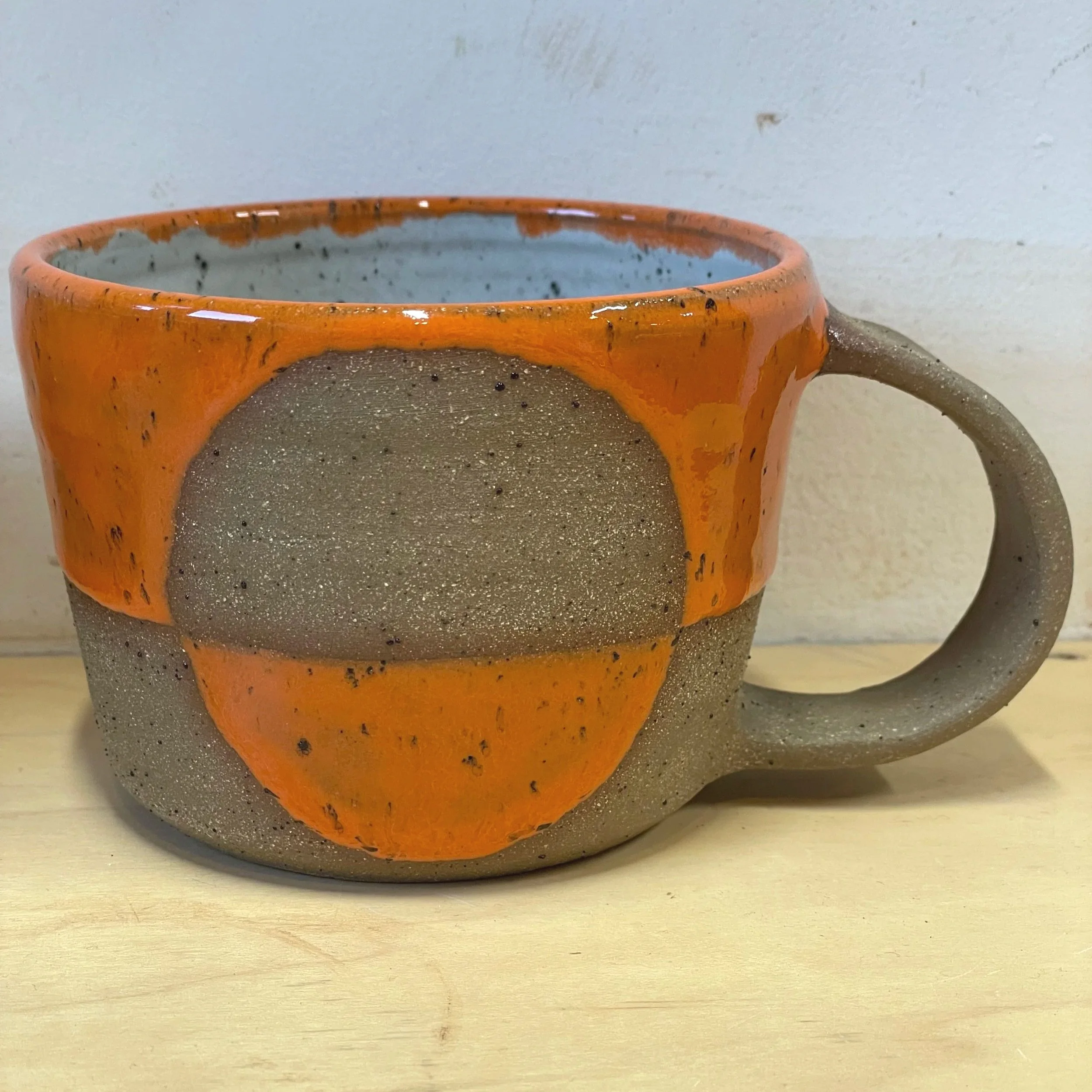 Handmade wheel thrown gloss bright orange glaze with half-circle on brown clay with speckles mug modern design stoneware mid century modern