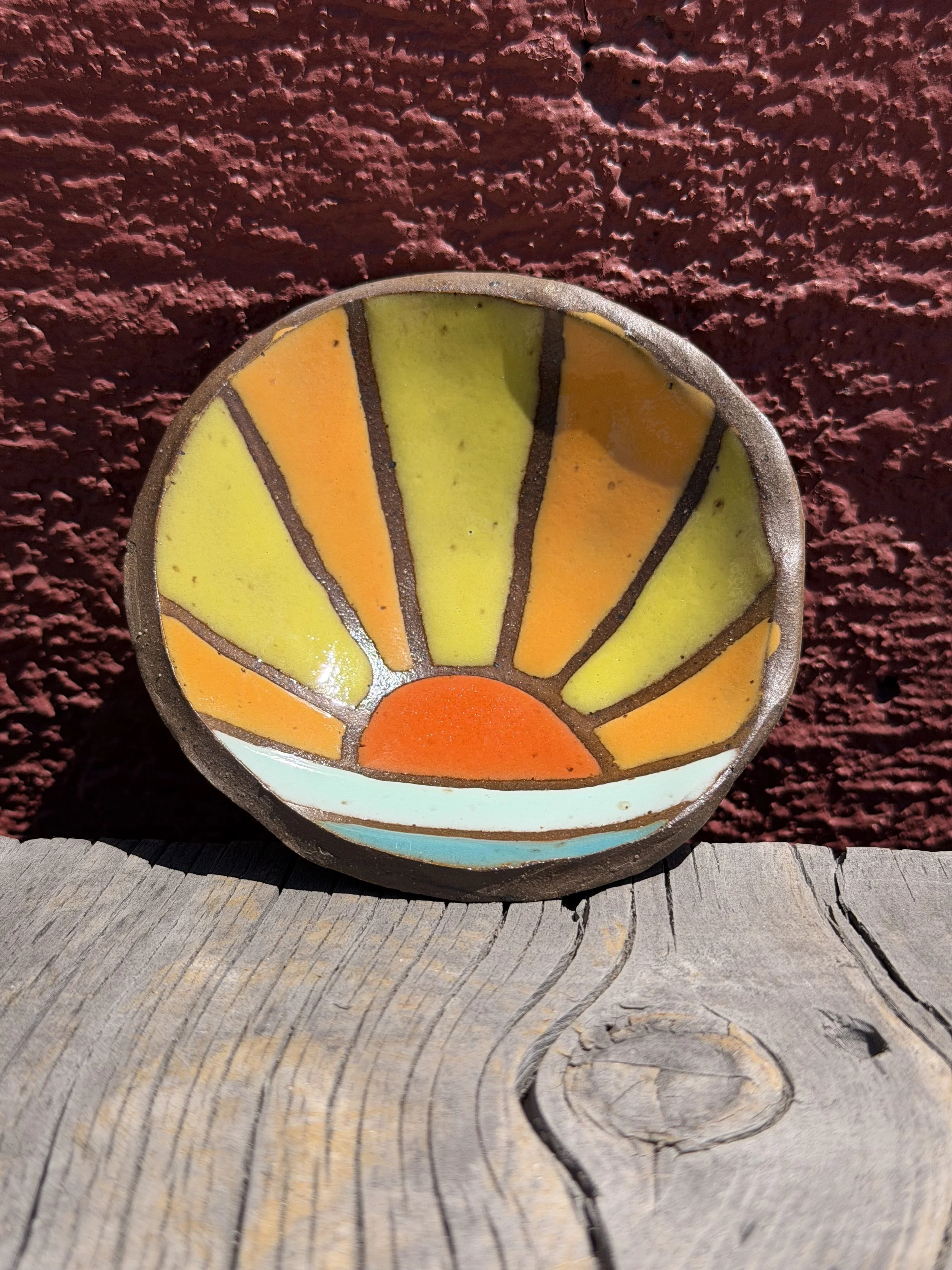 Multi-colored sun rays on water dish in brown speckled clay