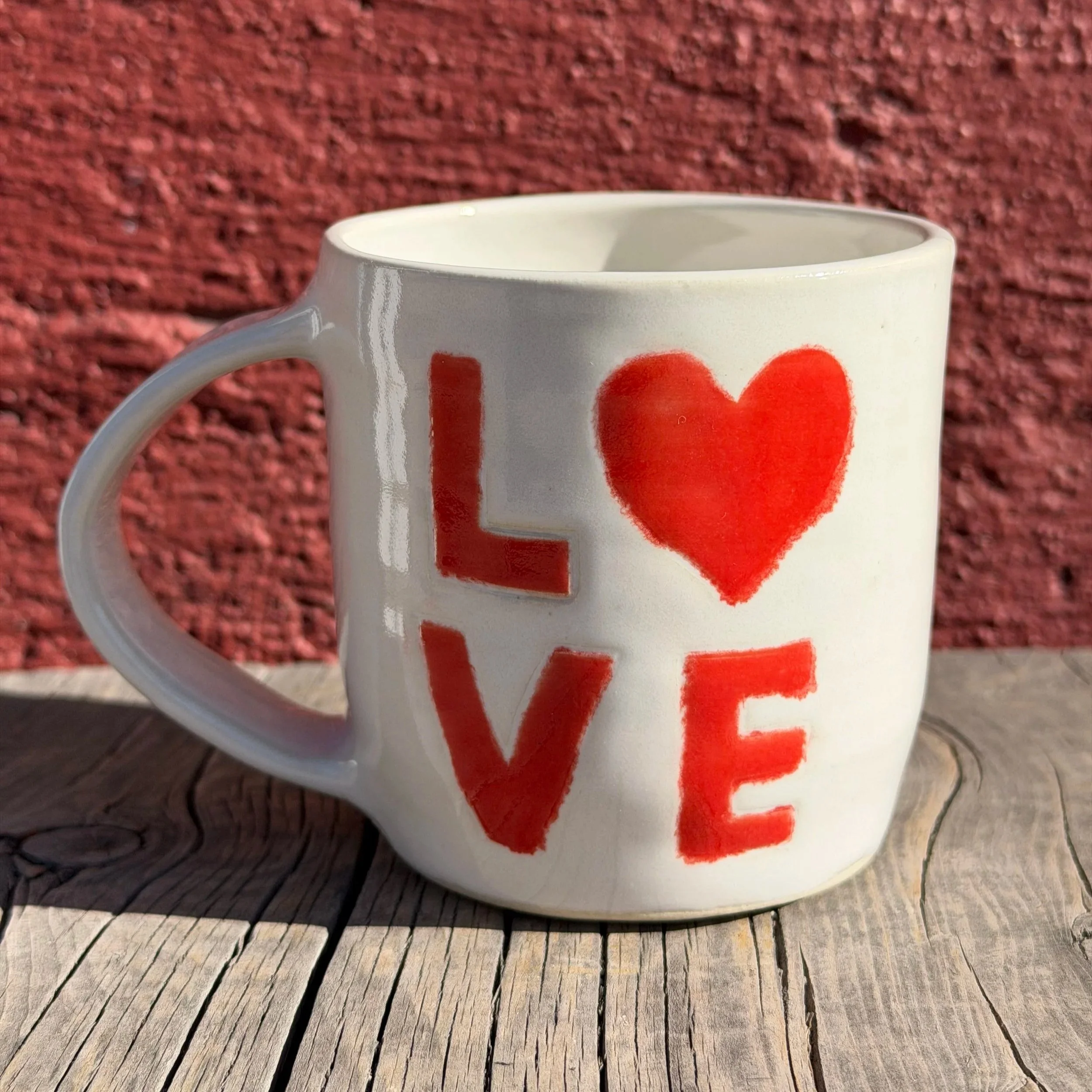 Handmade wheel-thrown stoneware mug in white clay with two sided red Love word typography where the “O” is replaced with a heart