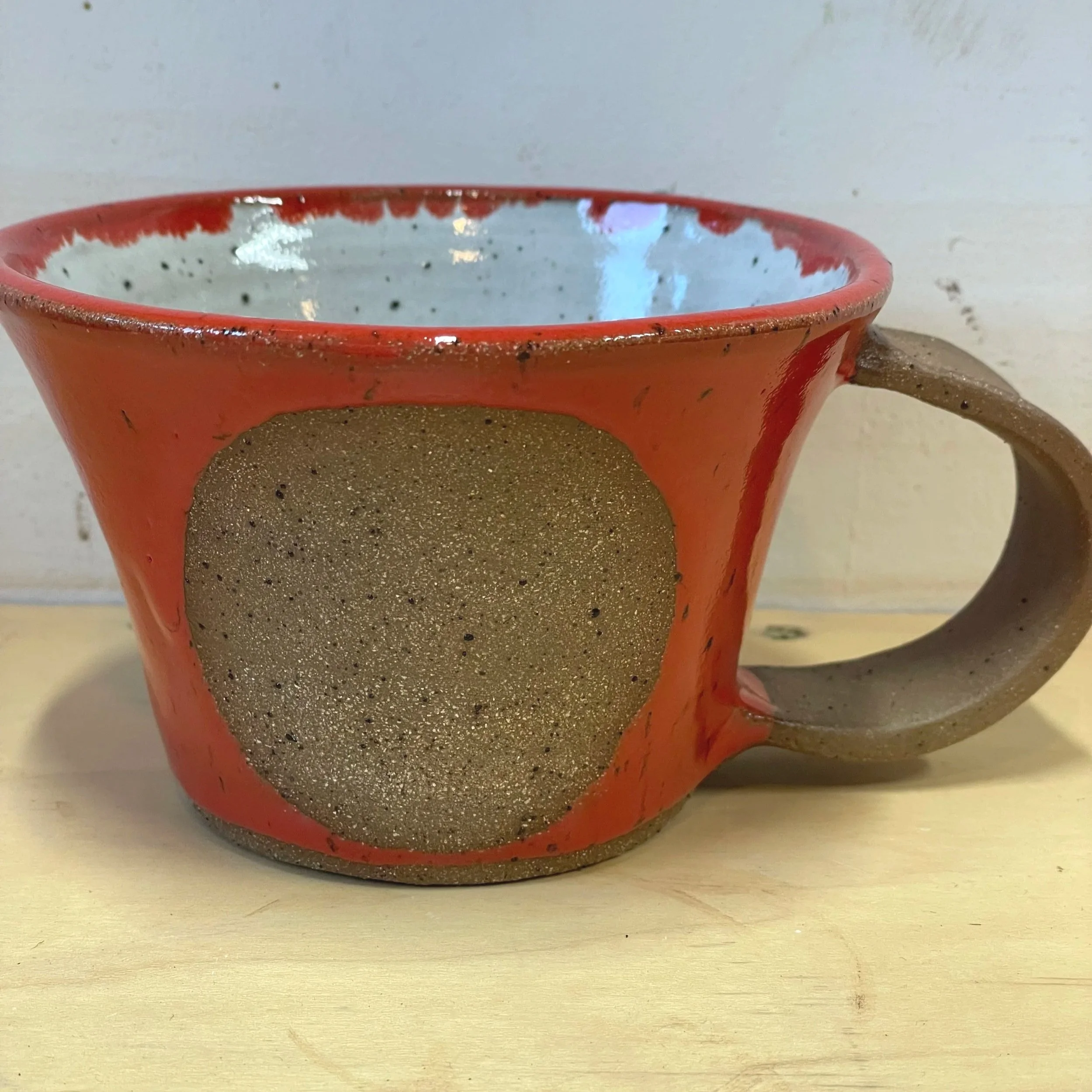 Handmade wheel thrown red gloss glaze with circle on brown clay with speckles mug modern design stoneware mid century modern