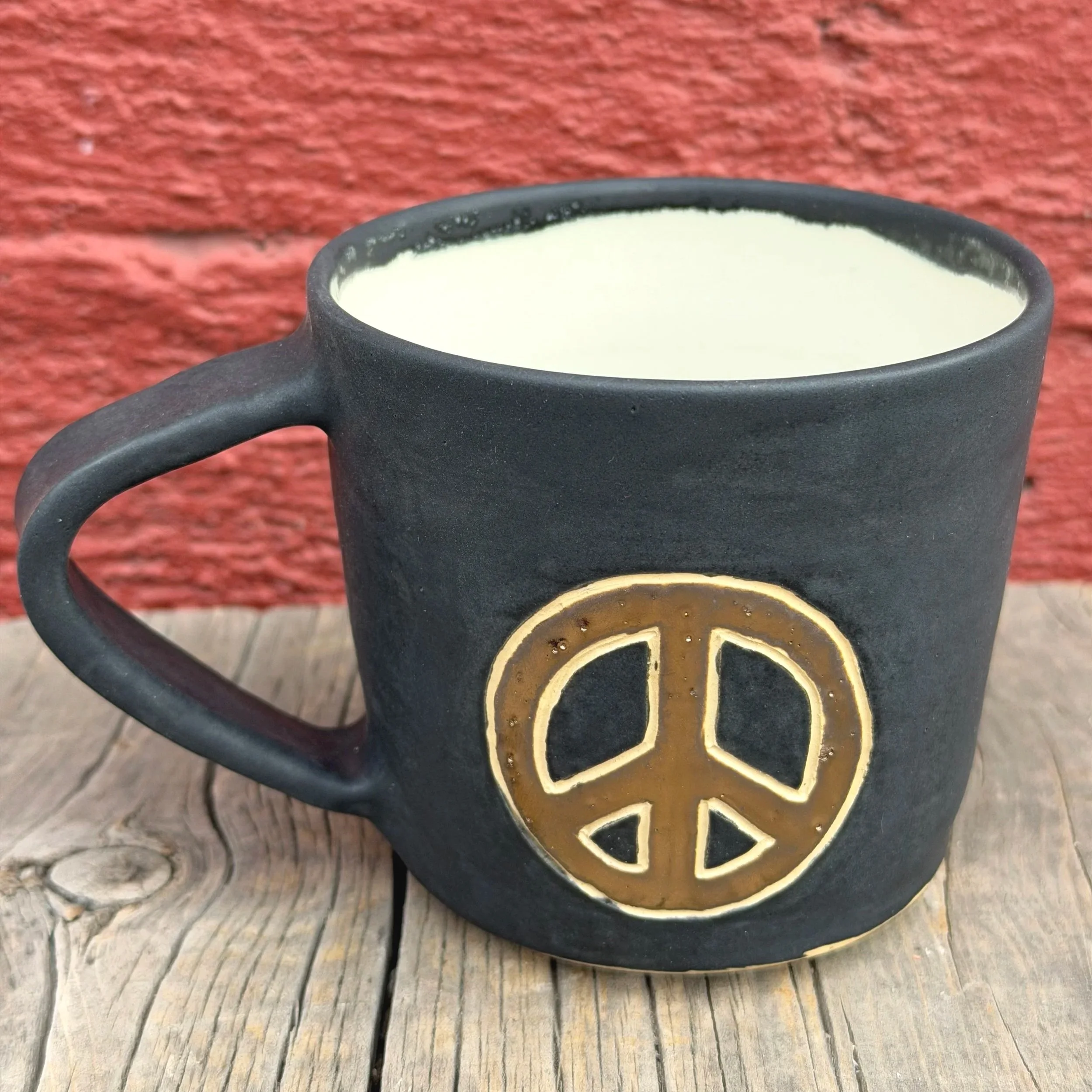 Handmade wheel thrown gold peace sign with black matte glaze on white clay mug modern design stoneware
