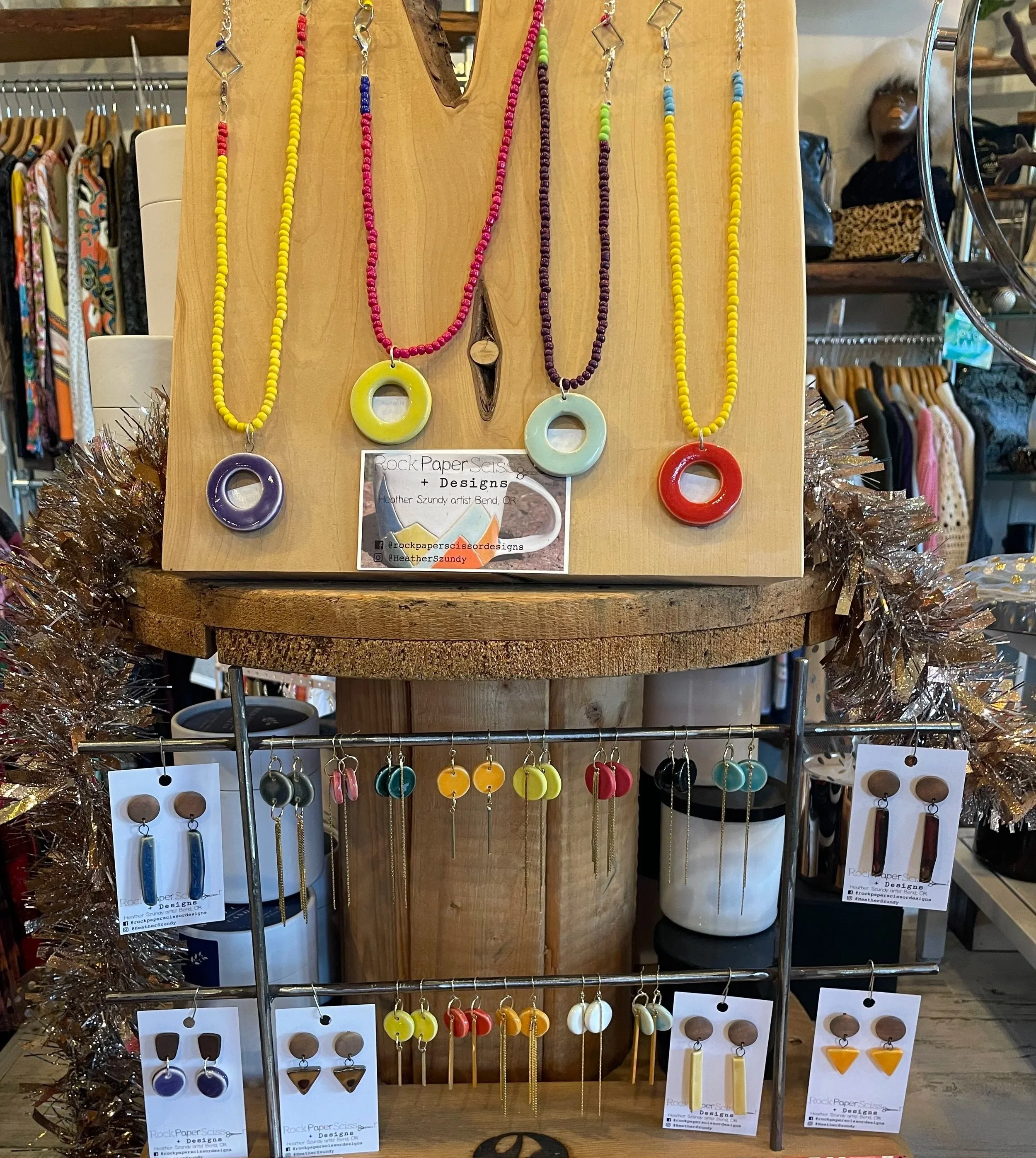 Colorful bead necklaces and earrings displayed on a wooden and metal jewelry stand in a retail store.