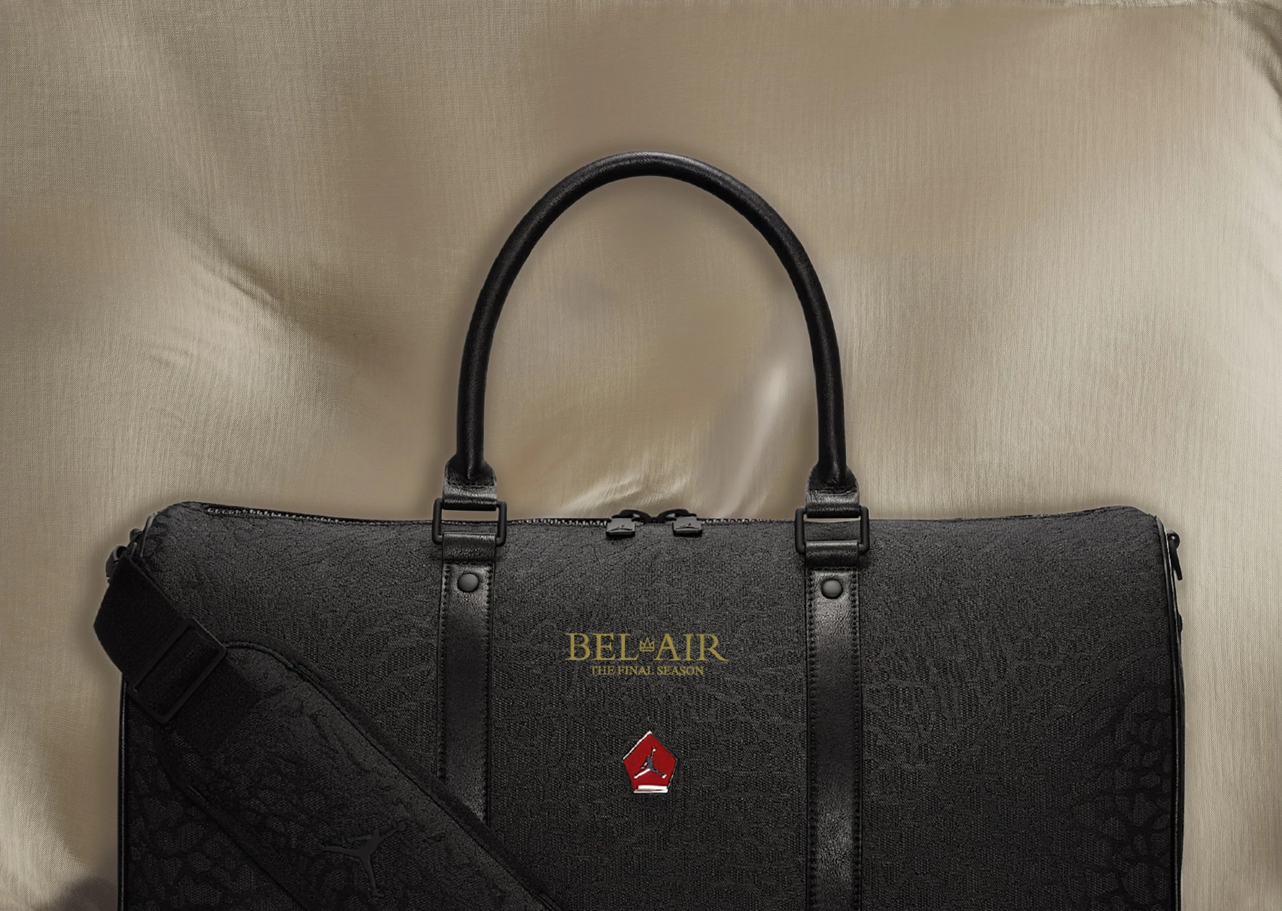 A black duffle bag with gold text and logo, sitting on a beige surface.