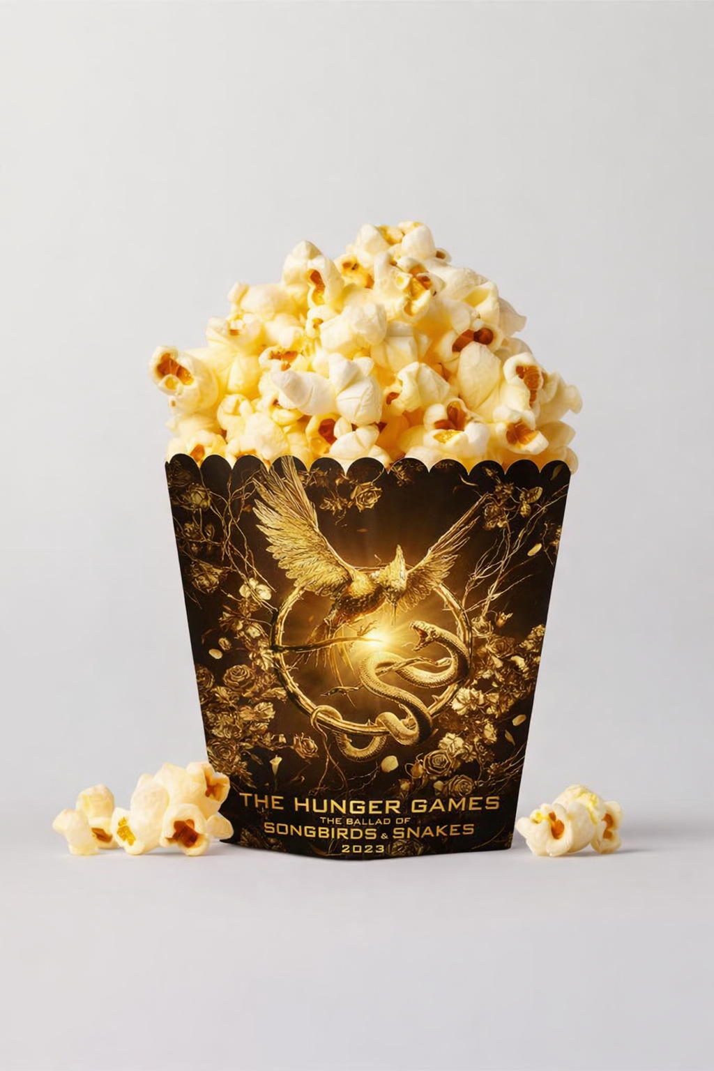 A bucket of popcorn with a Hunger Games themed design featuring a mockingjay and snake emblem, with the text "The Hunger Games: The Ballad of Songbirds and Snakes 2023."