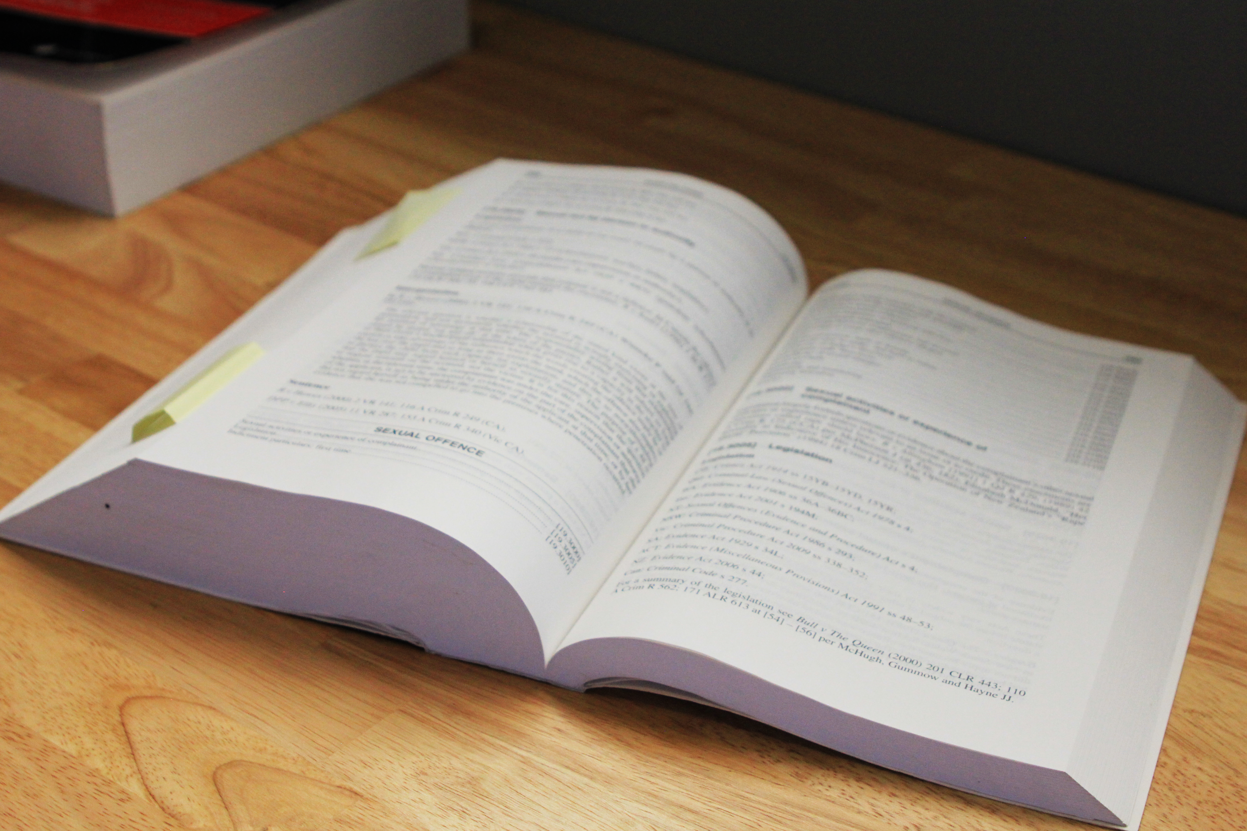 Open law book with sticky notes on a wooden desk.