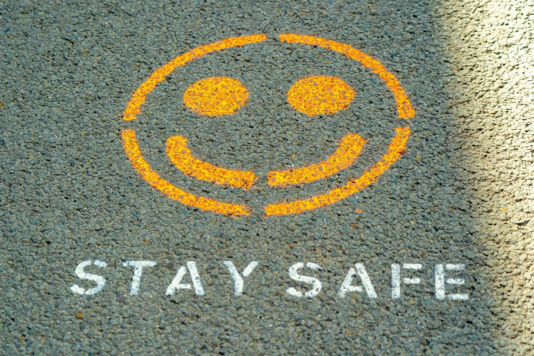 Smiley face and "Stay Safe" painted on concrete.