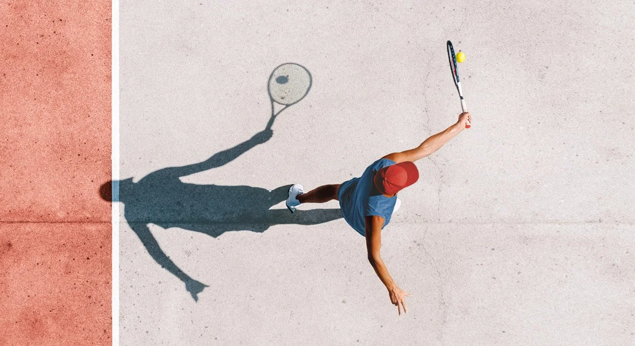 Mensch spielt Tennis auf einem Tennisplatz, Schatten wirft den Tennisball und Schläger auf den Boden.