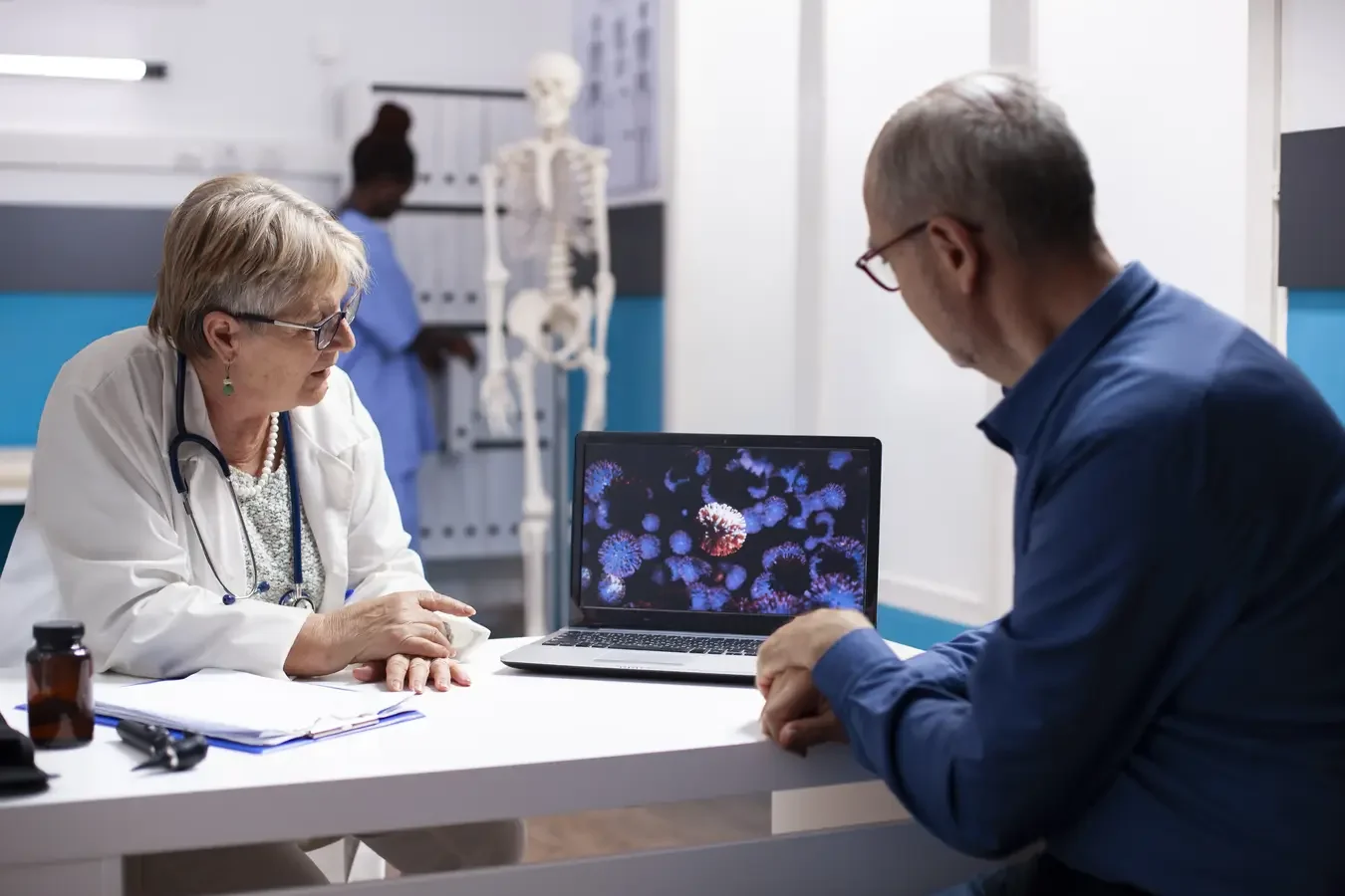 Female doctor and patient discussing medical information in front of a laptop displaying molecular structures, with a nurse in the background