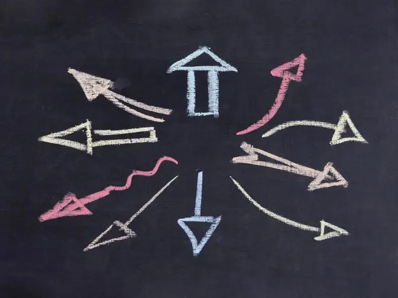 Colorful chalk arrows on a blackboard pointing in multiple directions, illustrating different paths or options.