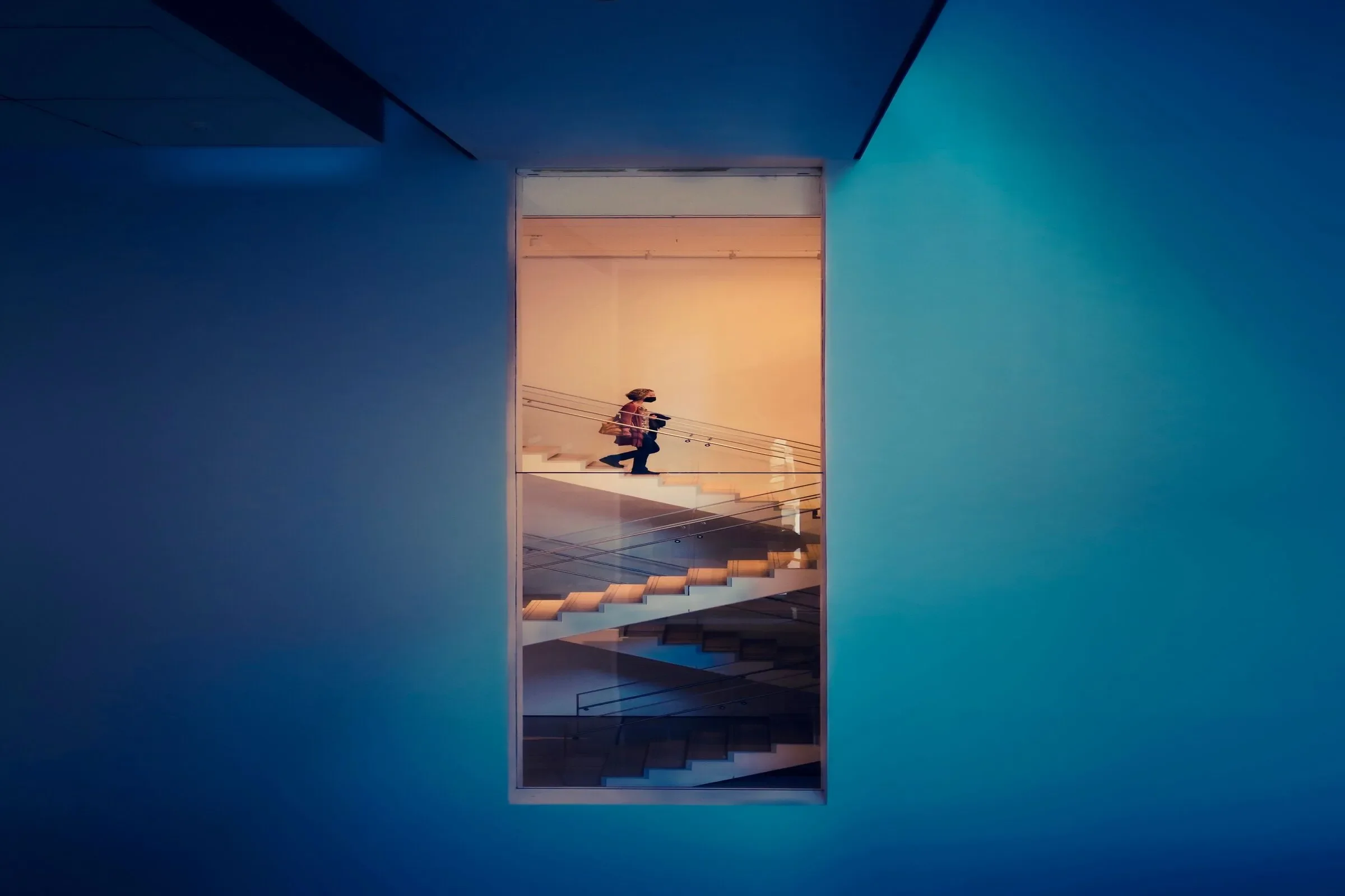 Modern architectural staircase illuminated by blue and golden light, representing business transformation, strategic progress and organizational change.