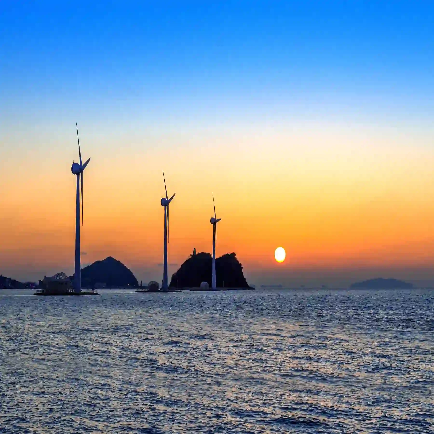 Wind turbines generating renewable electricity at sunset in South Korea, illustrating a market entry strategy for utility-scale clean energy investment and expansion.