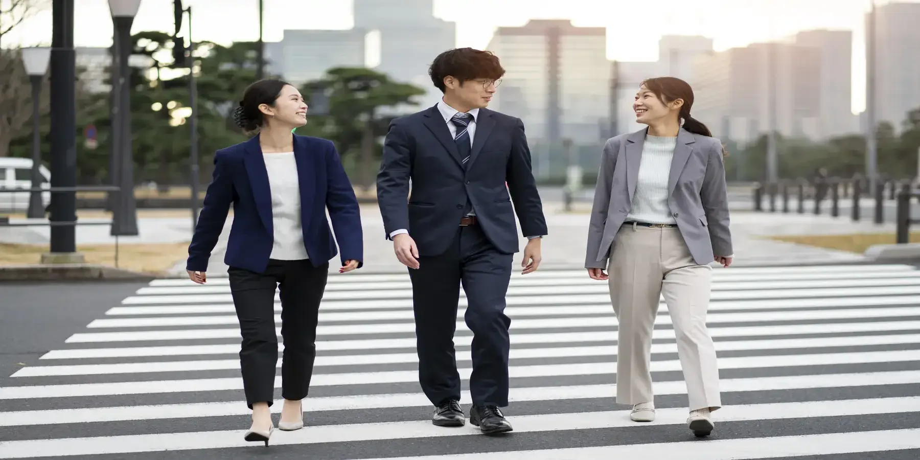 Three professionals walking side by side toward a business district, symbolizing hands-on partnership in helping brands succeed in a new market.