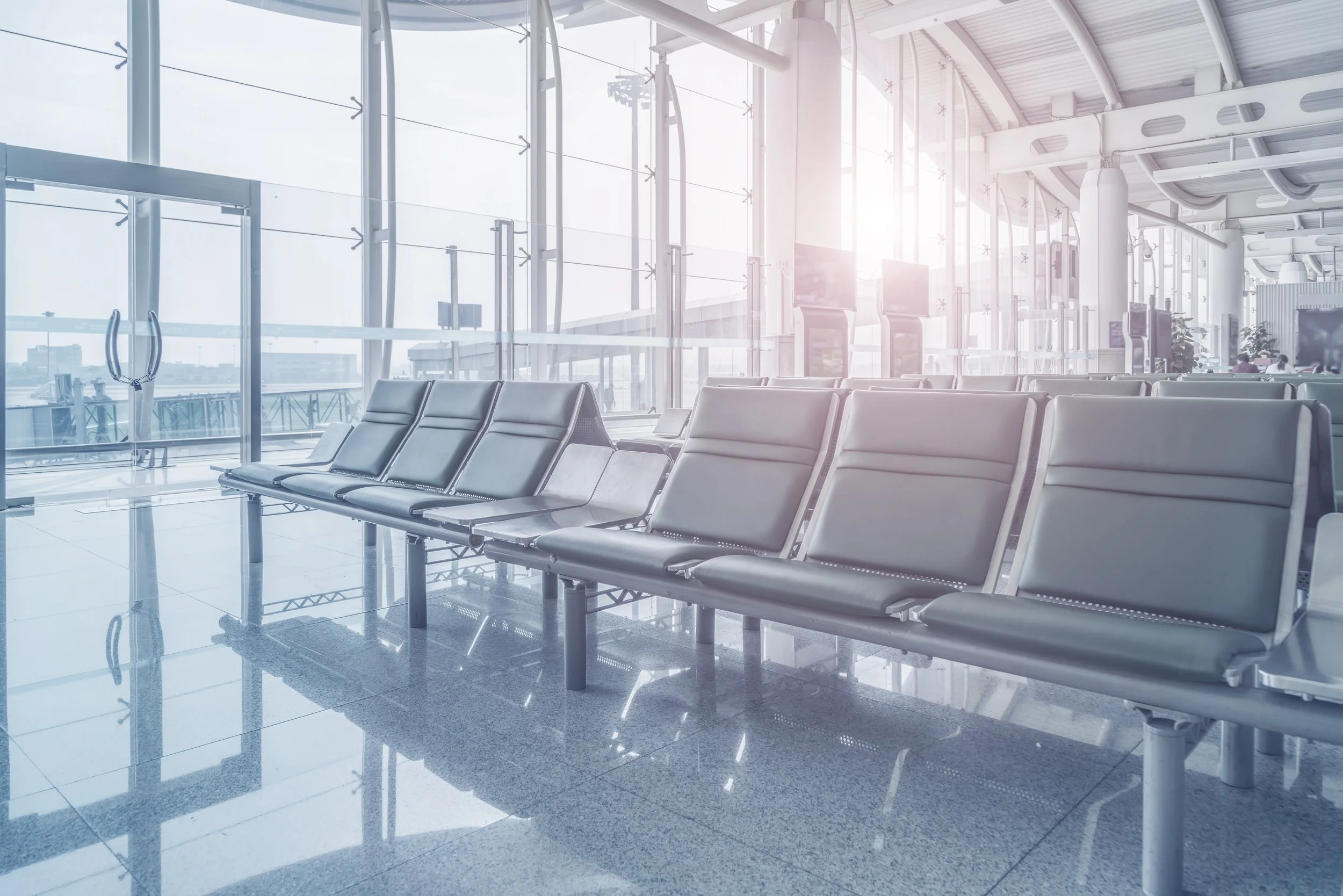 Quiet airport window with soft daylight and no visible planes, symbolizing pause and strategic transition