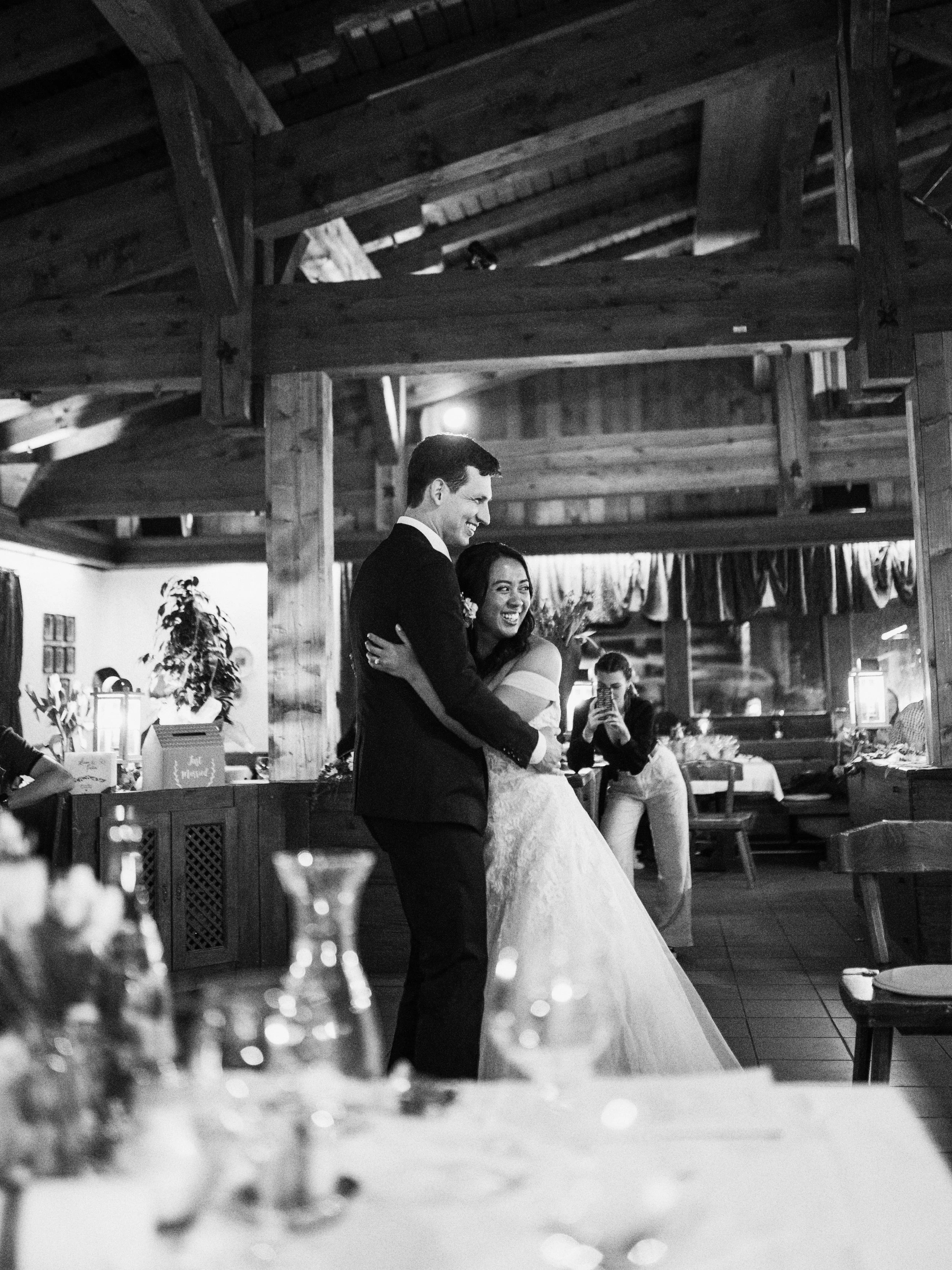 Ein Brautpaar tanzt in einem rustikalen Restaurant mit holzverzierten Wänden während ihrer Hochzeit, umgeben von Gästen, die das Fest genießen.