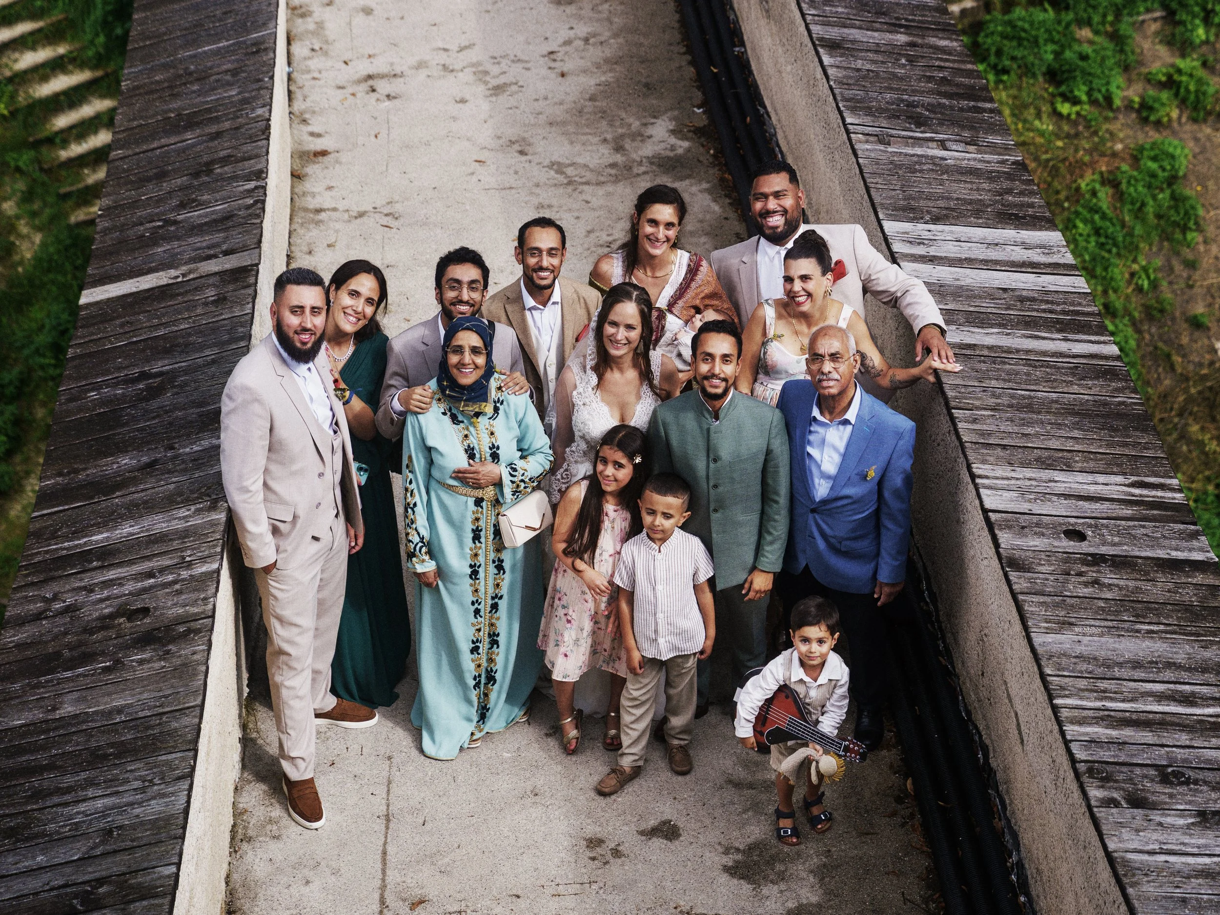 Eine Gruppe von Menschen, die auf einer Terrasse steht, die von Holz umgeben ist, bei einer Hochzeitsfeier