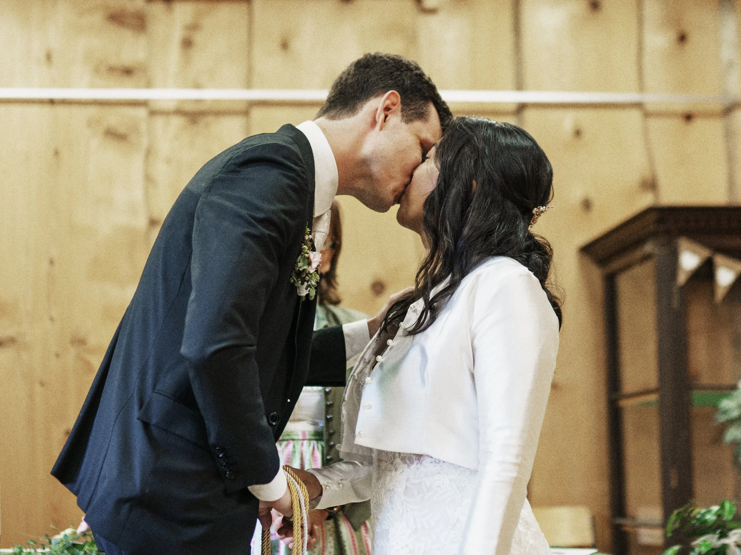 Ein Brautpaar küsst sich bei einer Hochzeit in einem Holzraum.