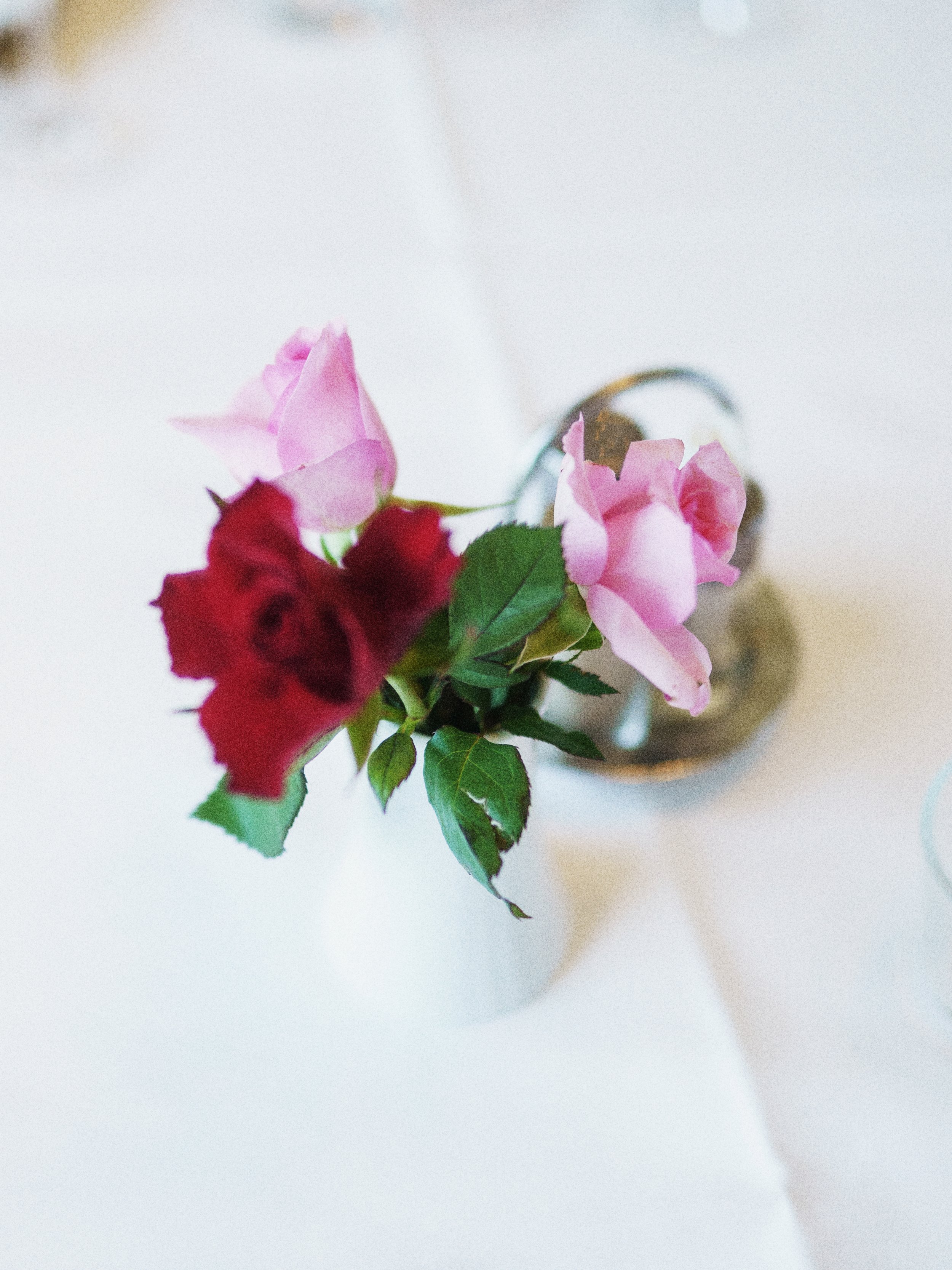 Blumenstrauß mit roten und rosa Rosen in einer Vase auf einem weißen Tisch.