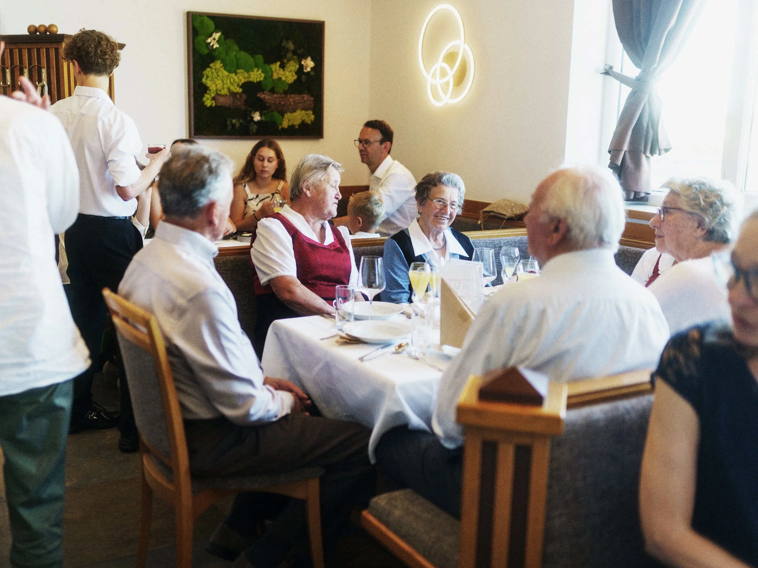 Menschen sitzen an einem schön gedeckten Tisch in einem Restaurant, während ein Kellner glaubt, Getränke zu servieren.