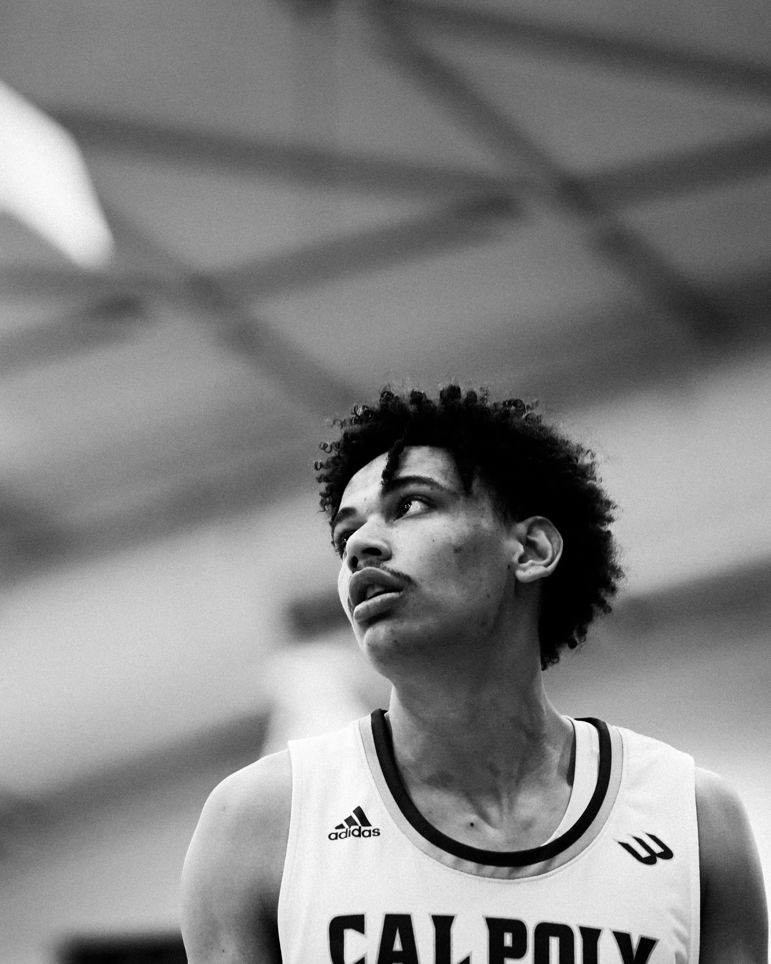 Black and white photo of a young male athlete in a Yale University basketball uniform looking off to the side.