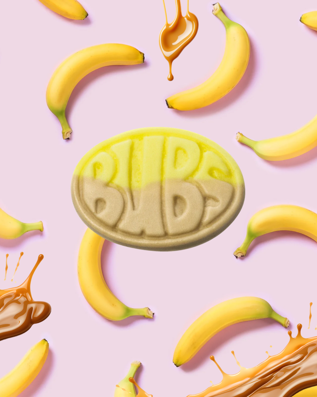 A Bidi Bid soap bar surrounded by bananas and caramel drops on a pink background.