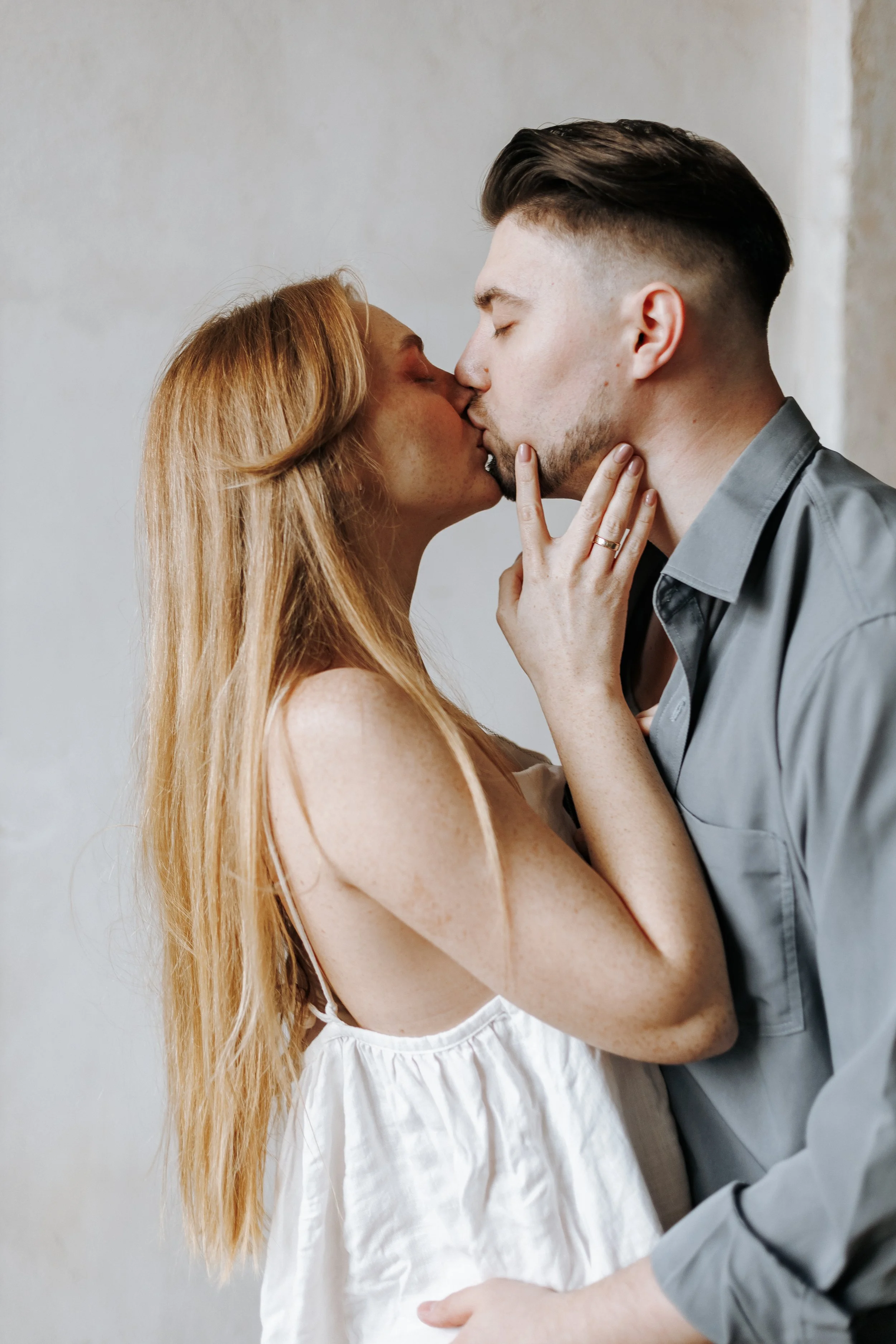 A man and woman sharing a kiss, with the woman touching the man's face with her hand.