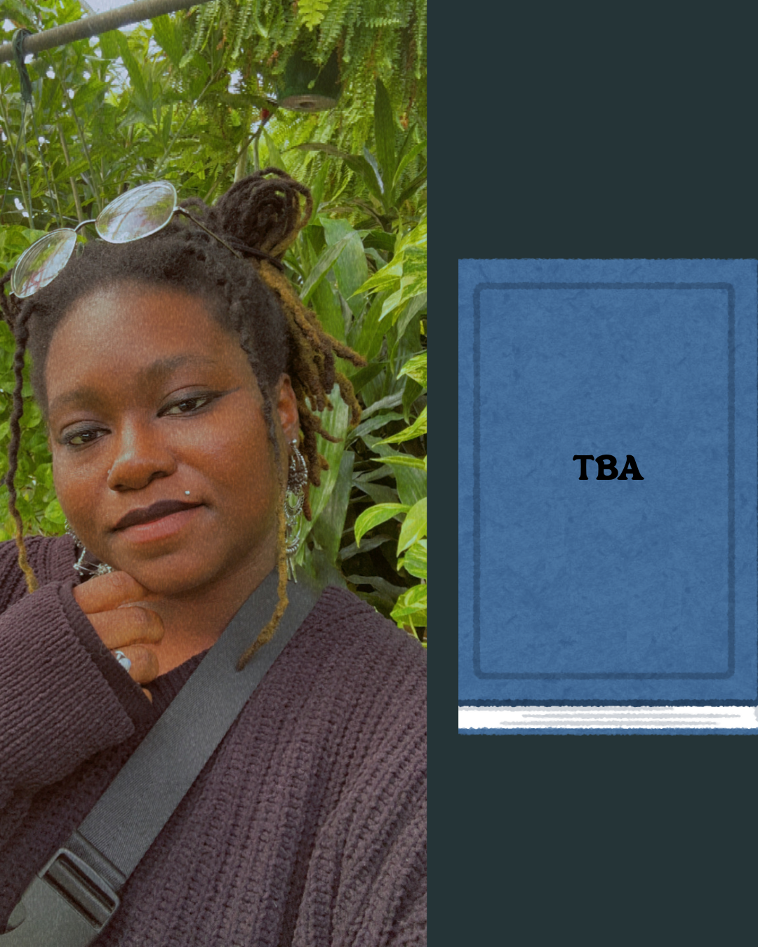 A woman with dreadlocks, wearing glasses on her head and jewelry, standing among green plants. She is wearing a dark brown sweater and has a black strap across her shoulder, with a contemplative expression.
