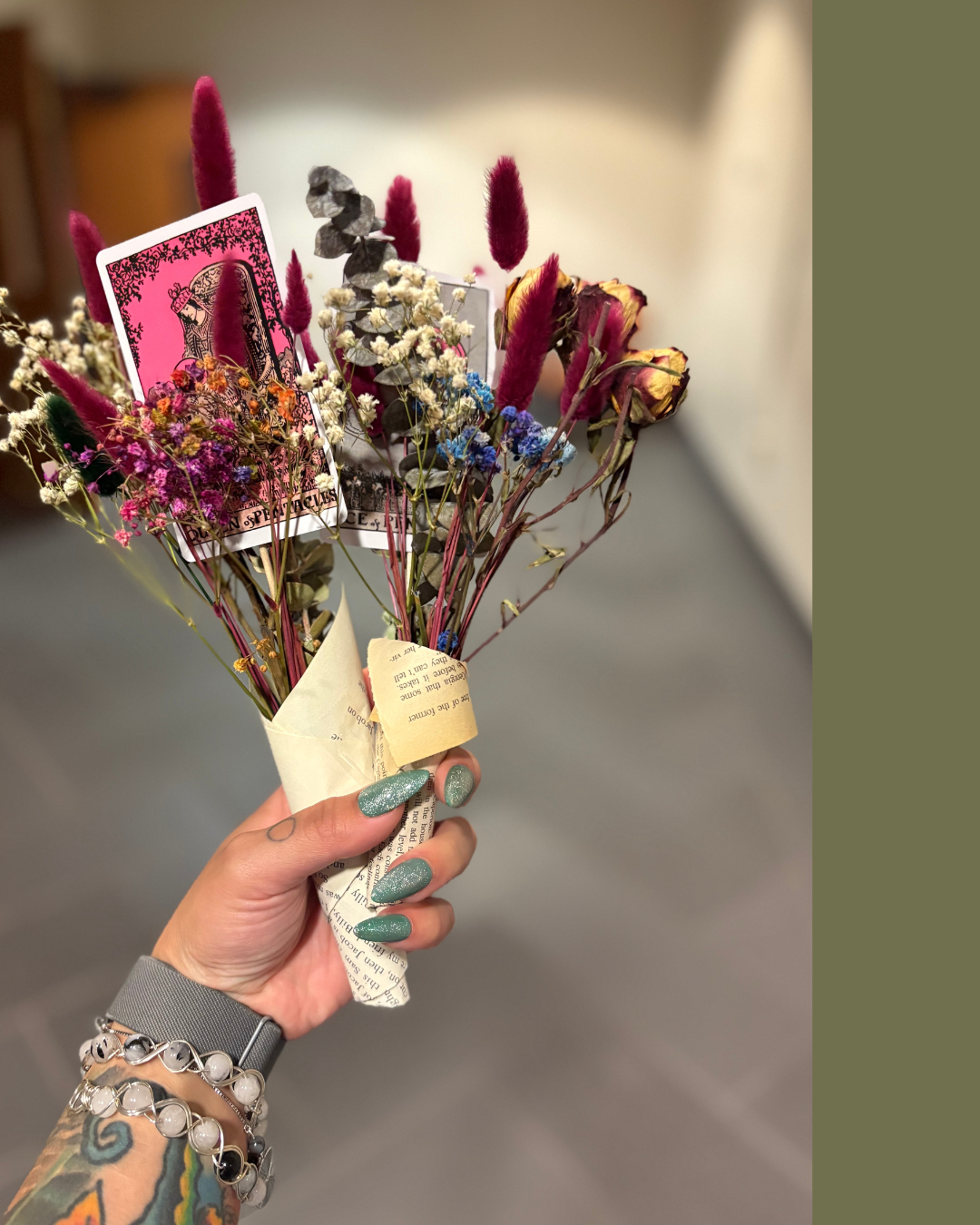 Hand holding a bouquet of dried flowers with a tarot card.