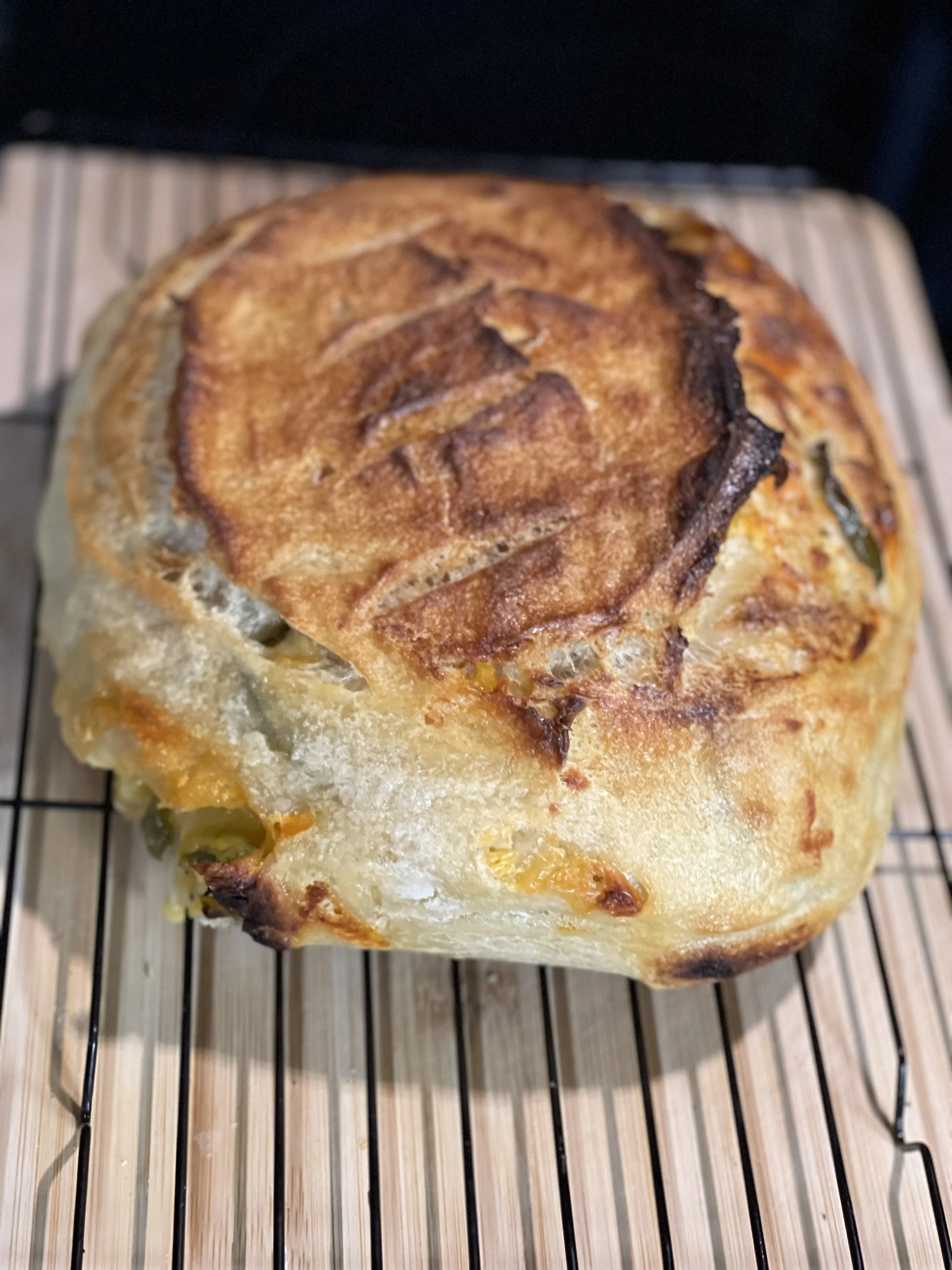 Freshly baked bread with a golden brown crust resting on a cooling rack.