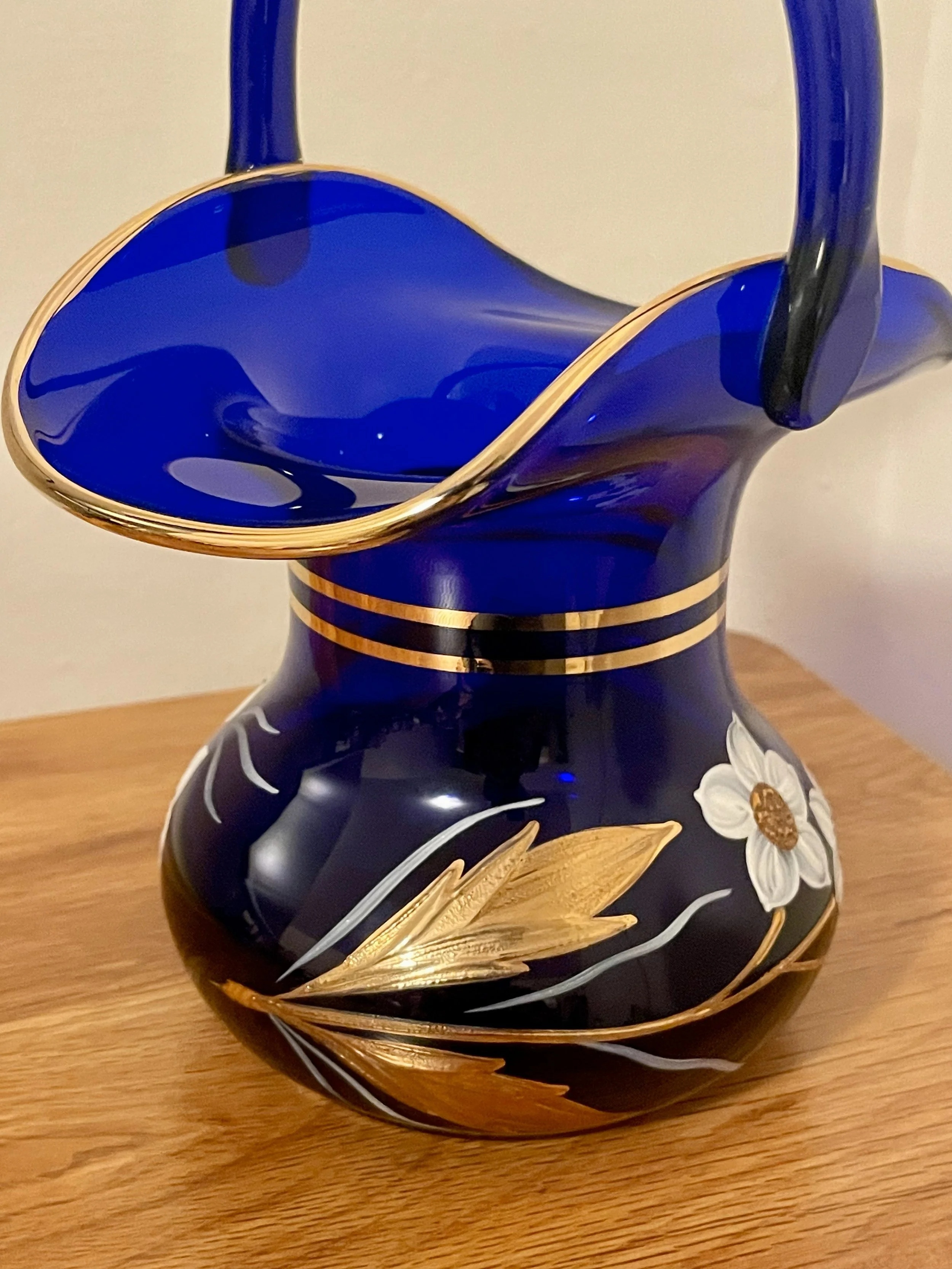 Decorative blue vase with gold accents and floral design on a wooden surface.