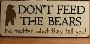 A sign that says 'DON'T FEED THE BEARS' with a silhouette of a bear and a smaller text underneath that says 'No matter what they tell you!'
