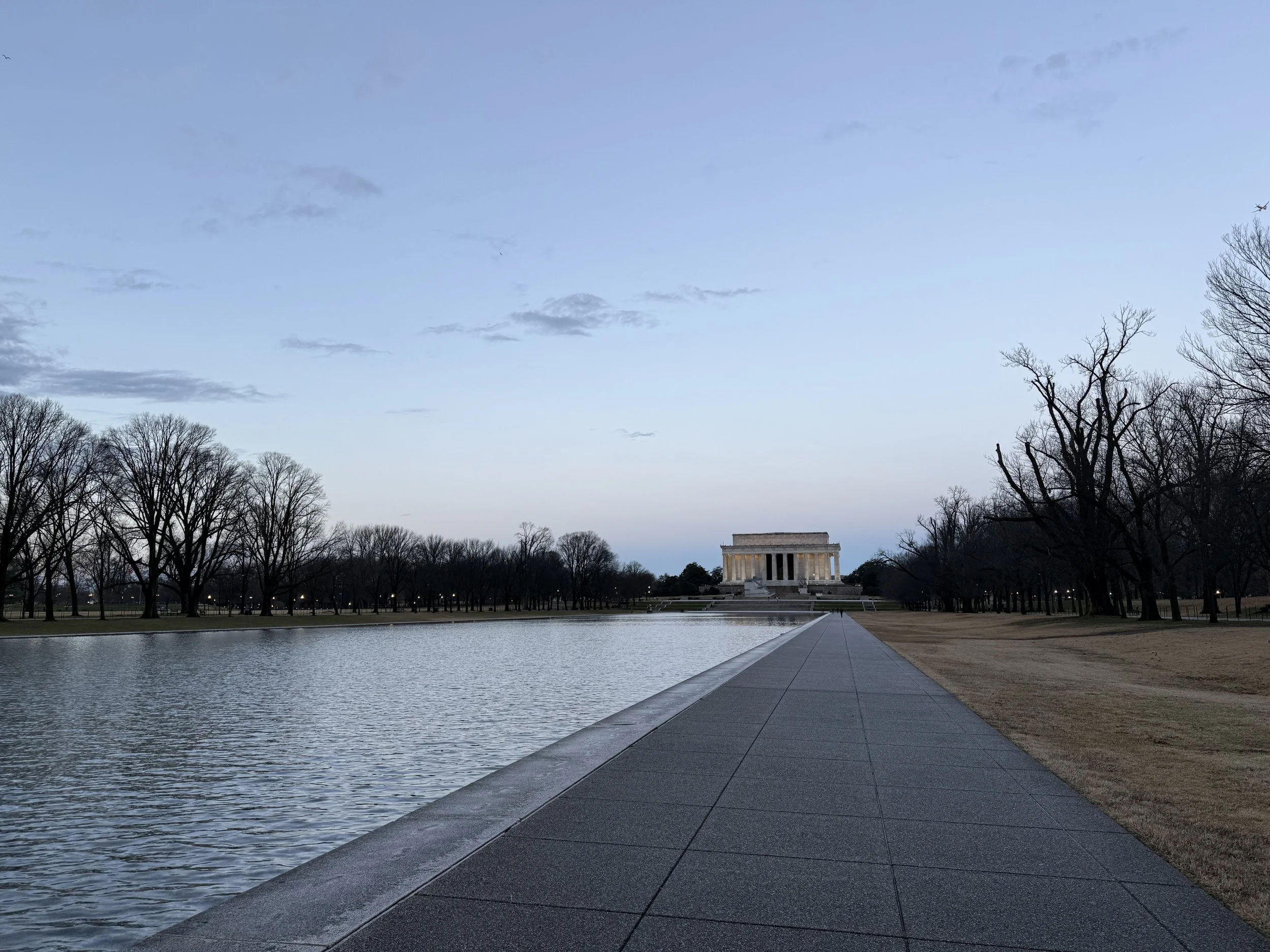 The Lincoln Memorial seen from the Reflecting Pool in Washington, D.C., during early evening with a mostly cloudy sky.