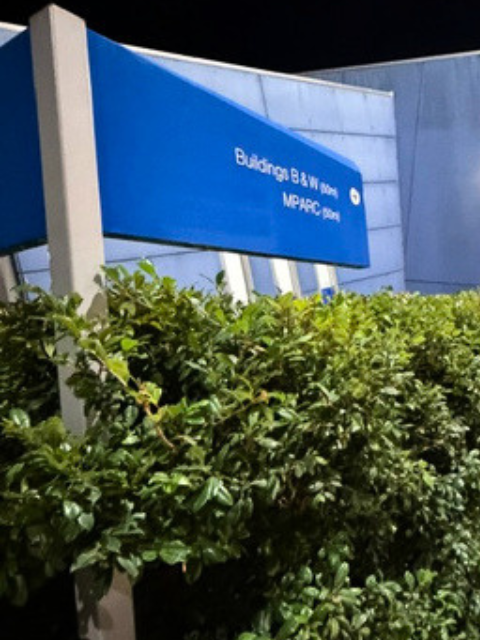 Blue sign at Badring B & W mall with green bushes in front.