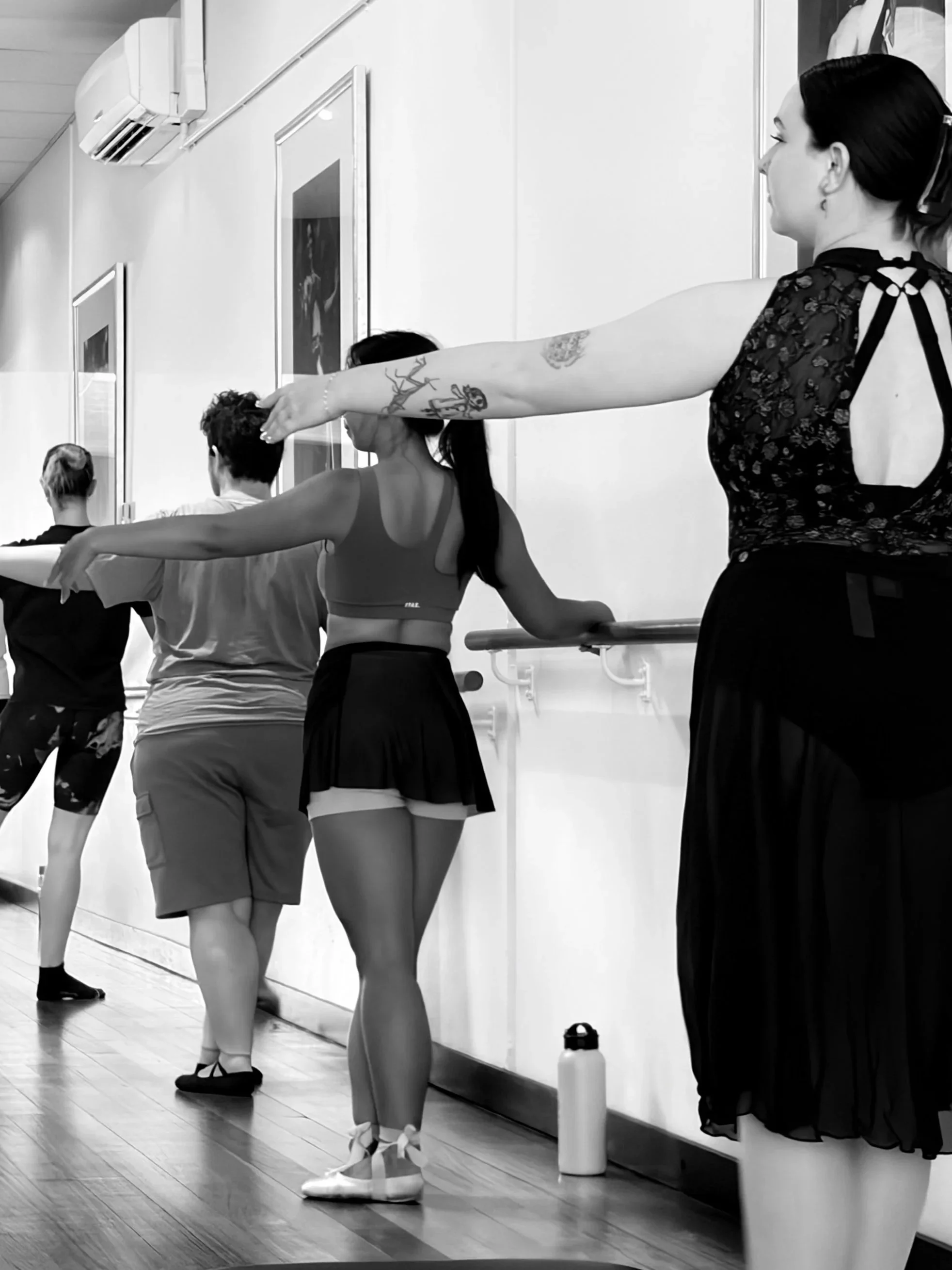 Ballet dancers practicing at a barre in a dance studio.