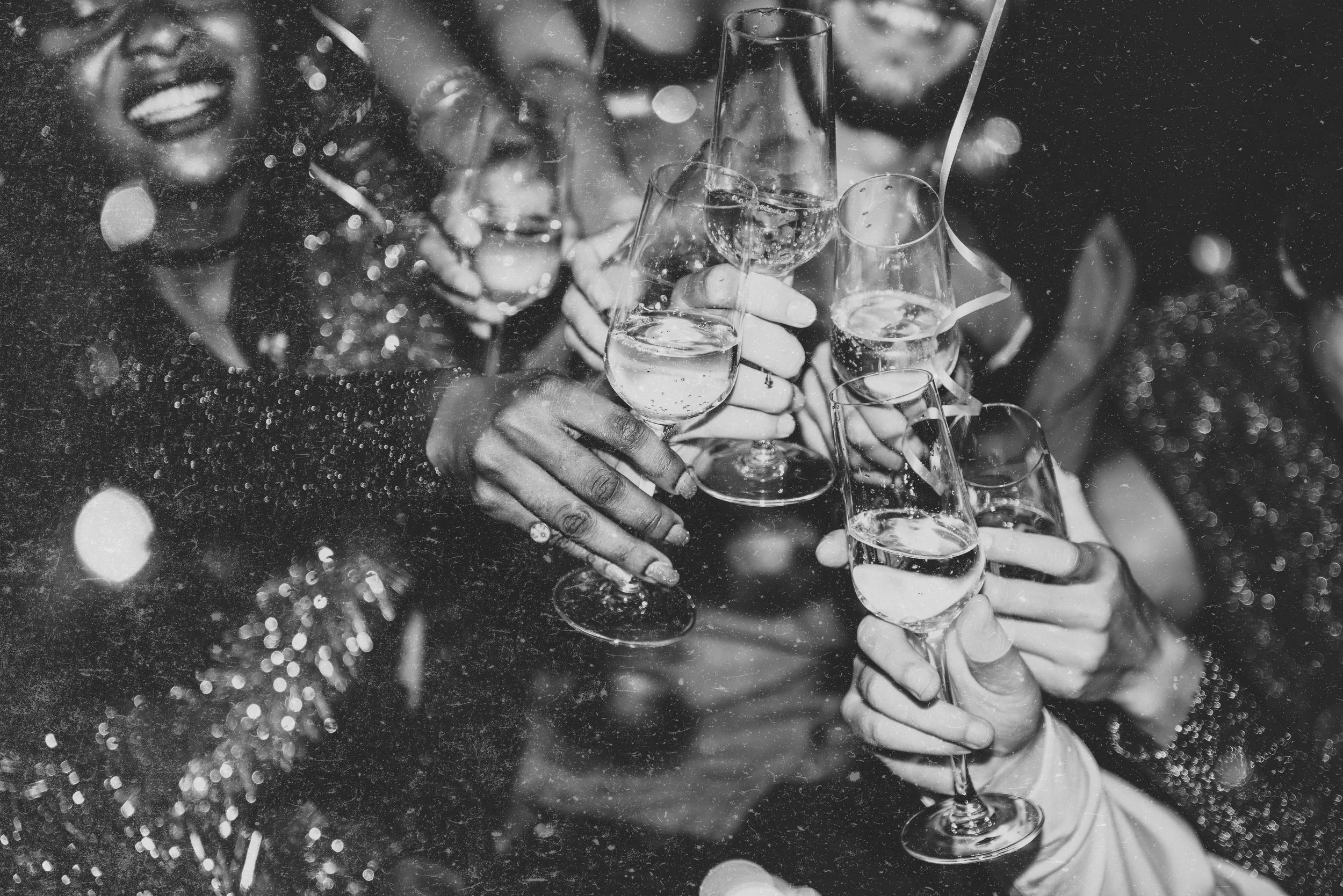 A group of people celebrating with champagne; they are clinking glasses filled with bubbly, and are dressed elegantly with festive decorations in the background.