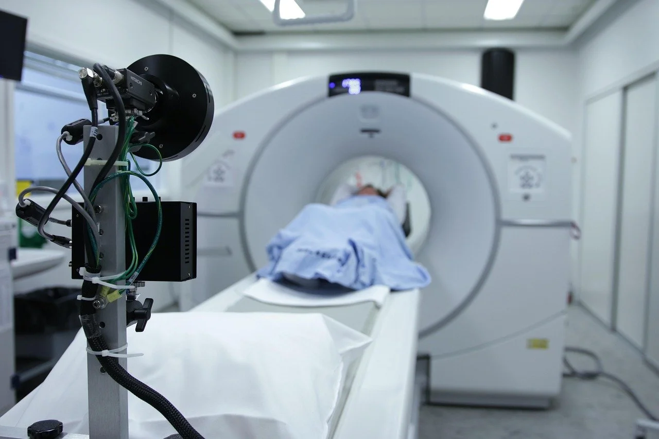 A patient lying on a hospital bed during a computed tomography (CT) scan in a medical imaging room.