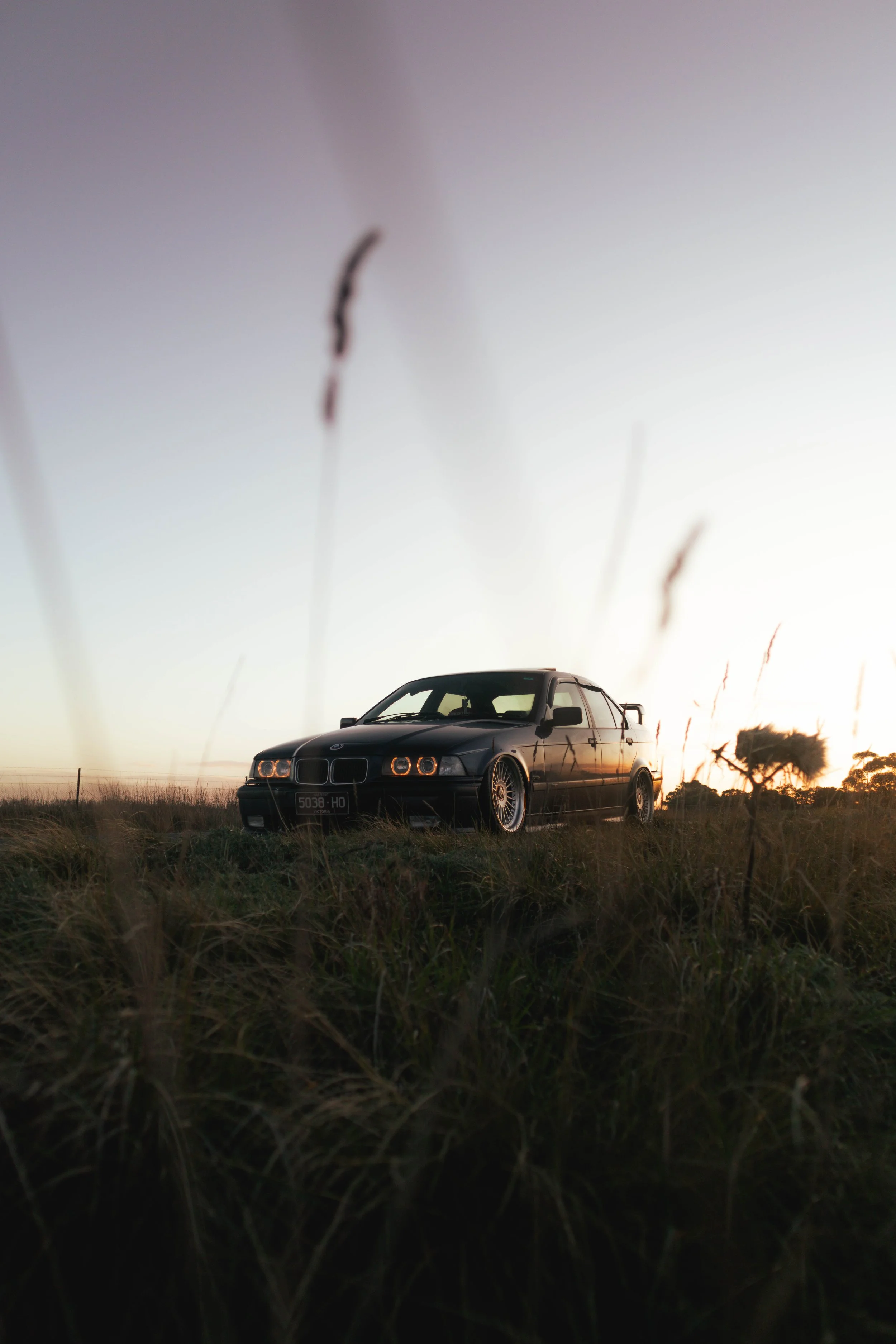 E36 parked on grassy field at sunset
