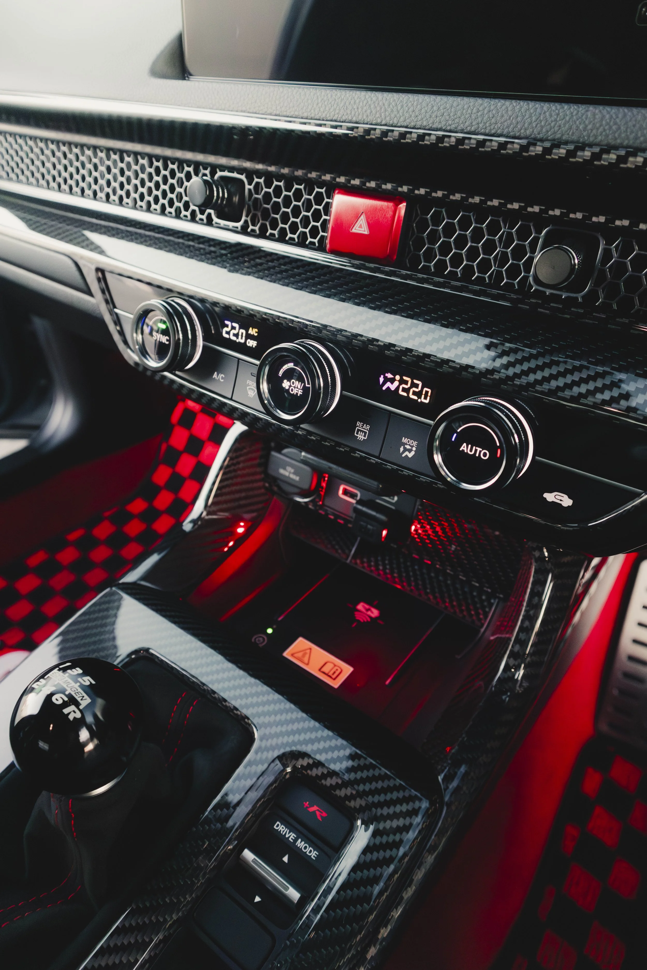 Close-up of a car interior featuring a carbon fiber dashboard with various controls.