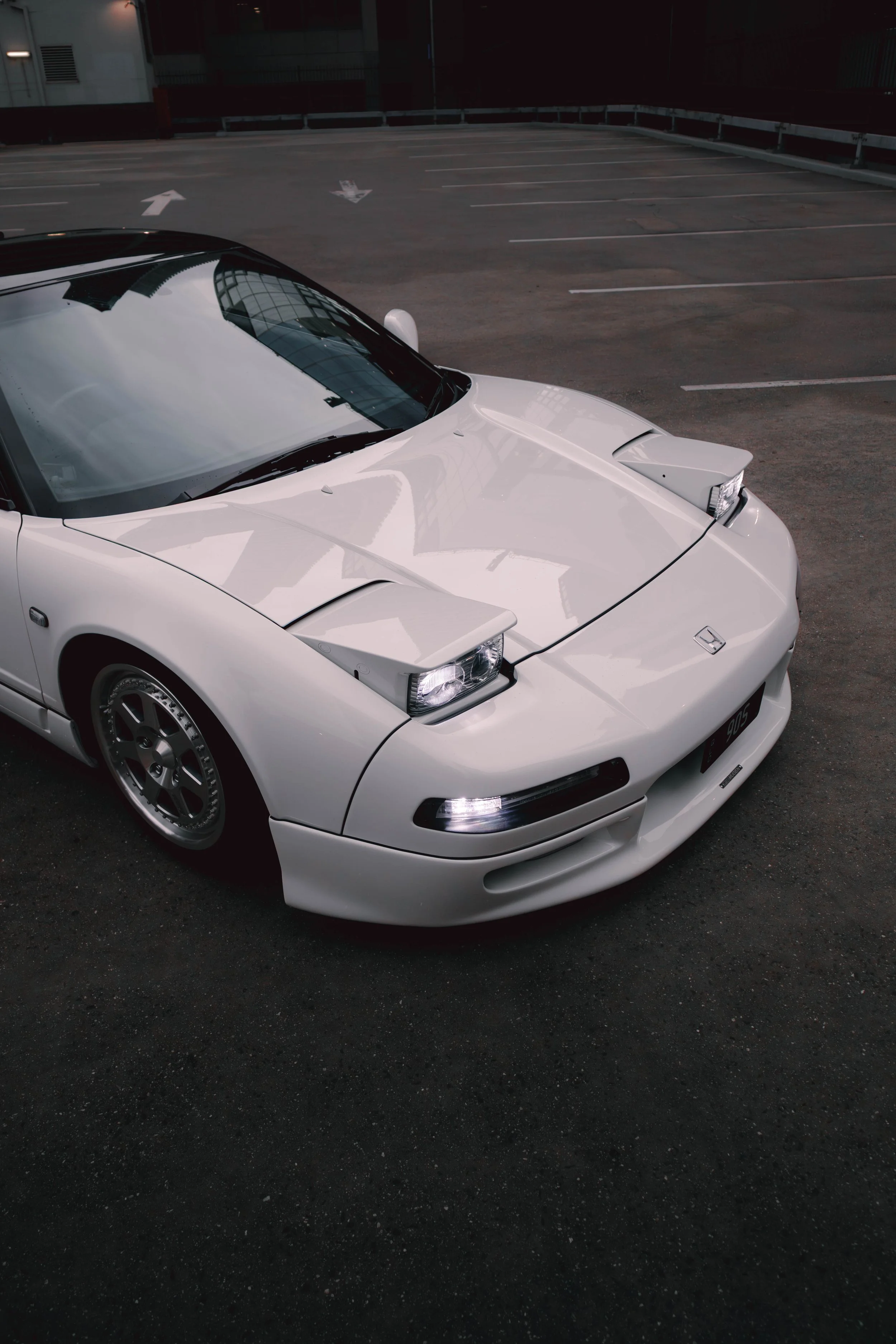 A white Honda NSX with Mugen parts in a parking lot.